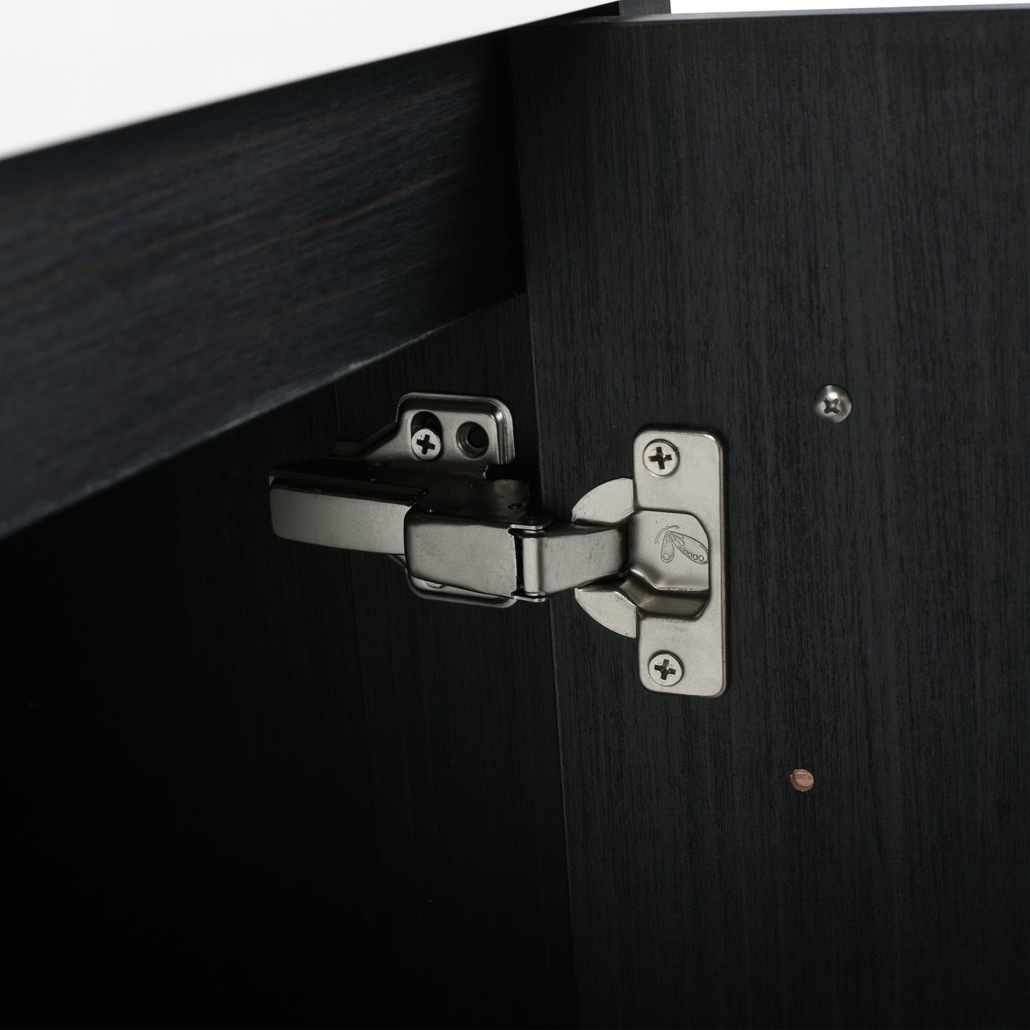 Closeup of a brushed nickel cabinet hinge on dark wood finish