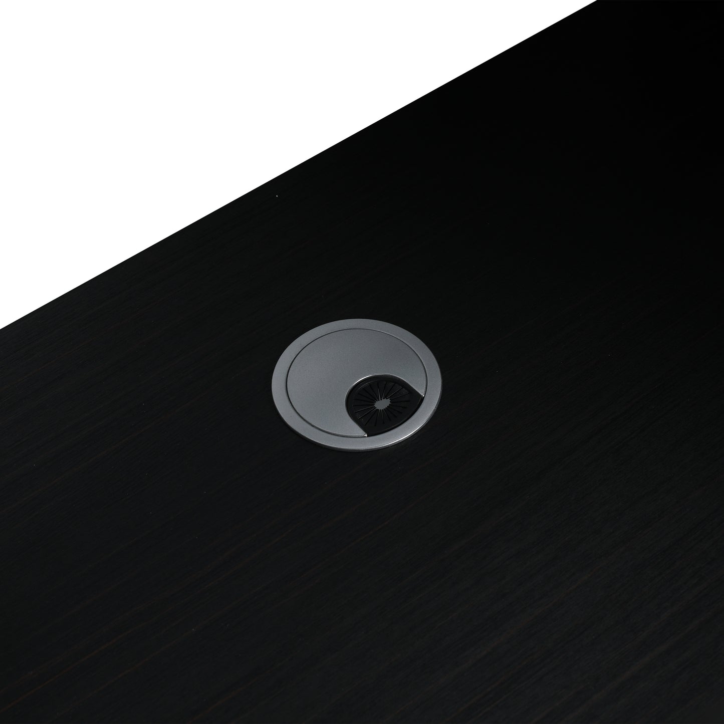 Dark wood grain desk surface with silver circular grommet and black brush insert for cable management