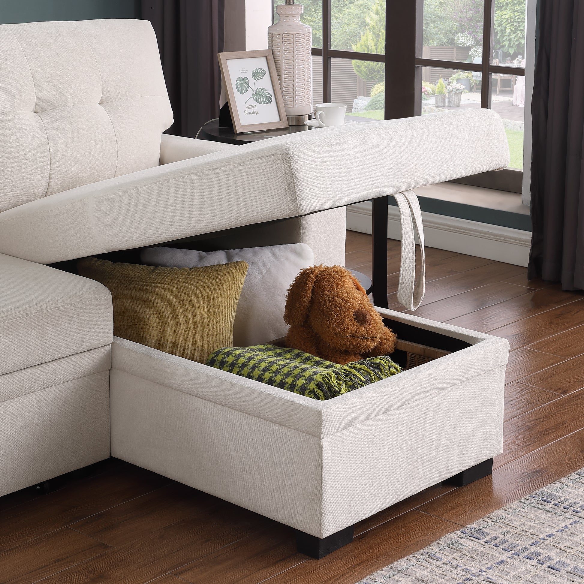 Cream tufted sectional sofa with open storage revealing pillows and blanket