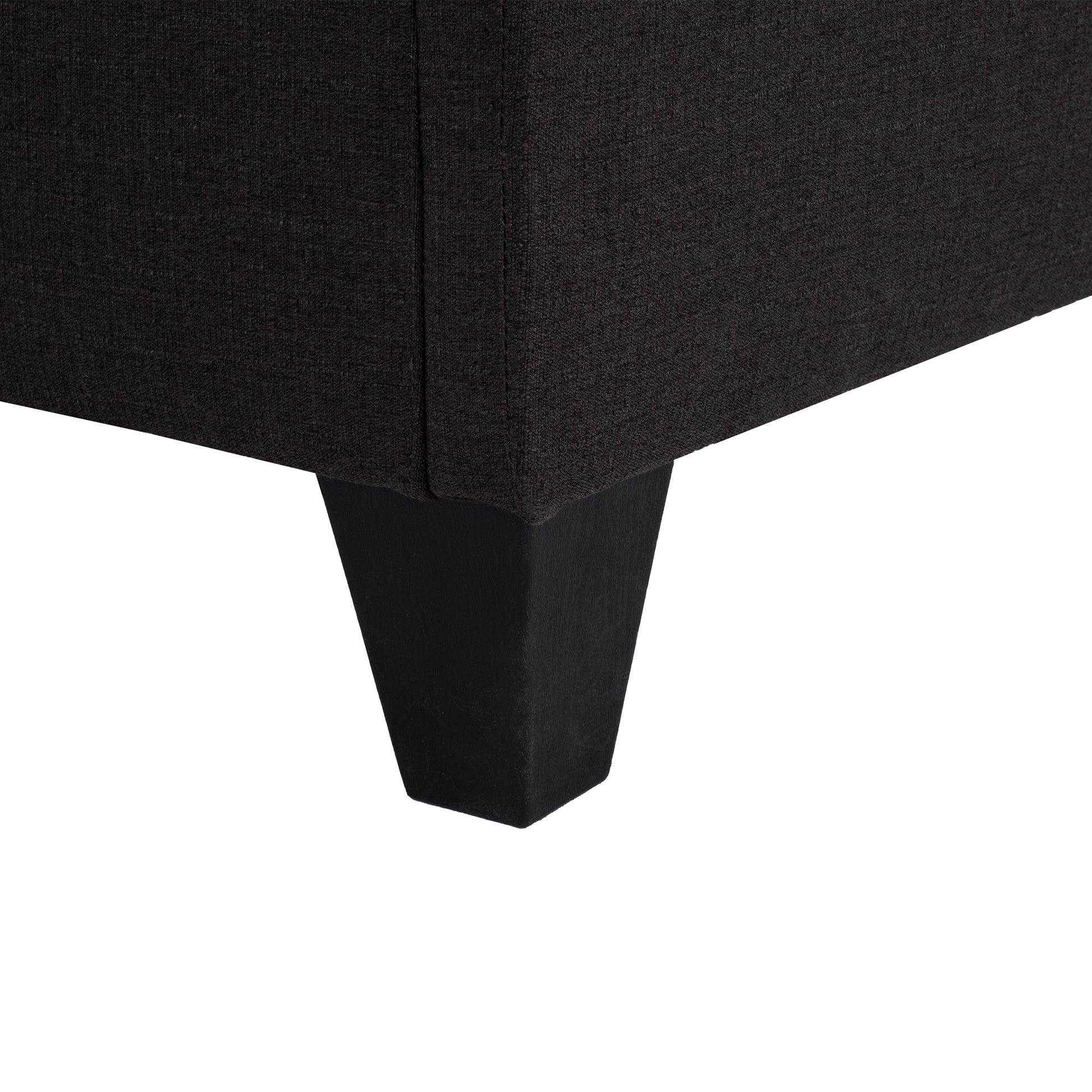 Dark gray textured fabric sofa corner with a tapered black wooden leg