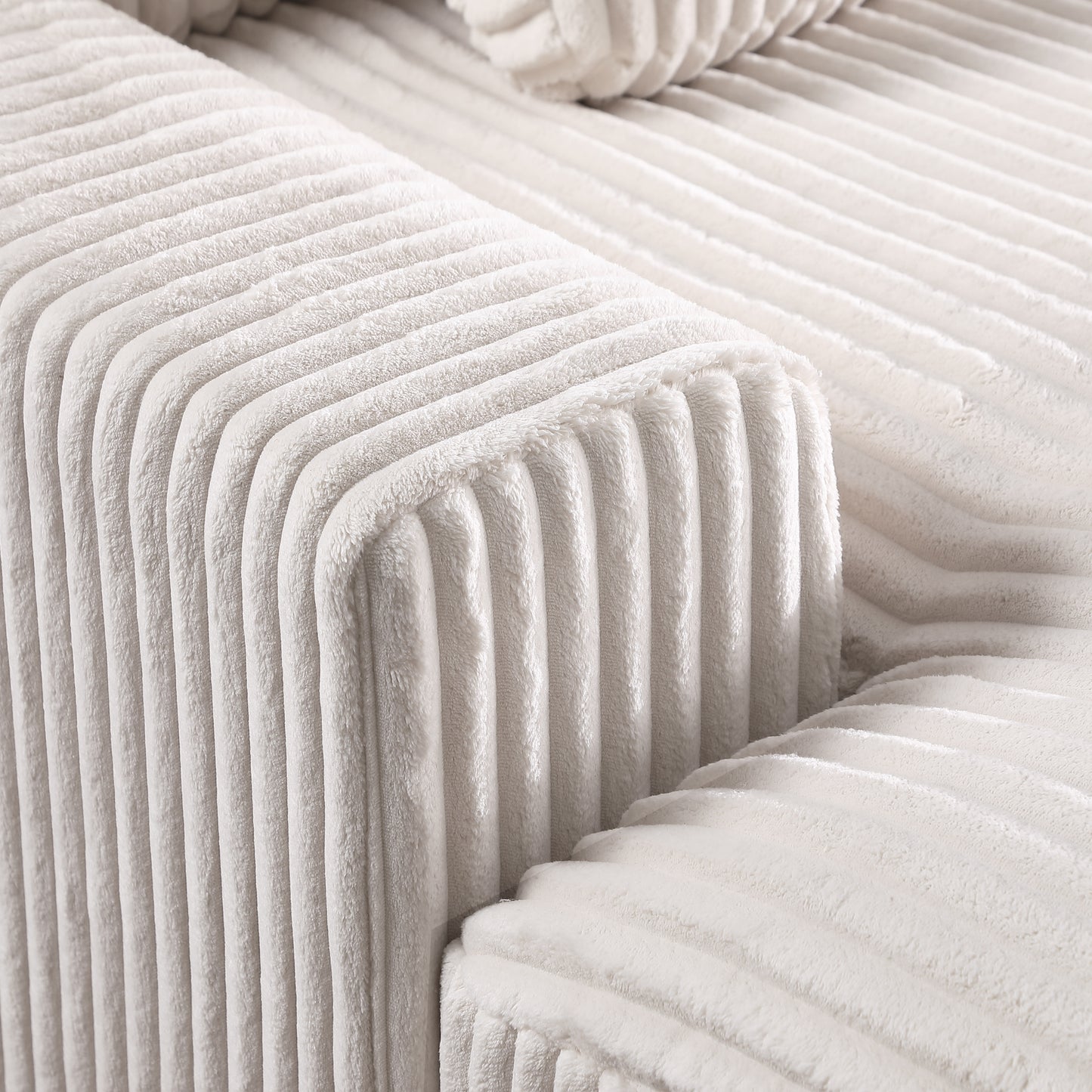 Closeup of soft ivory corduroy fabric texture on a plush sofa armrest