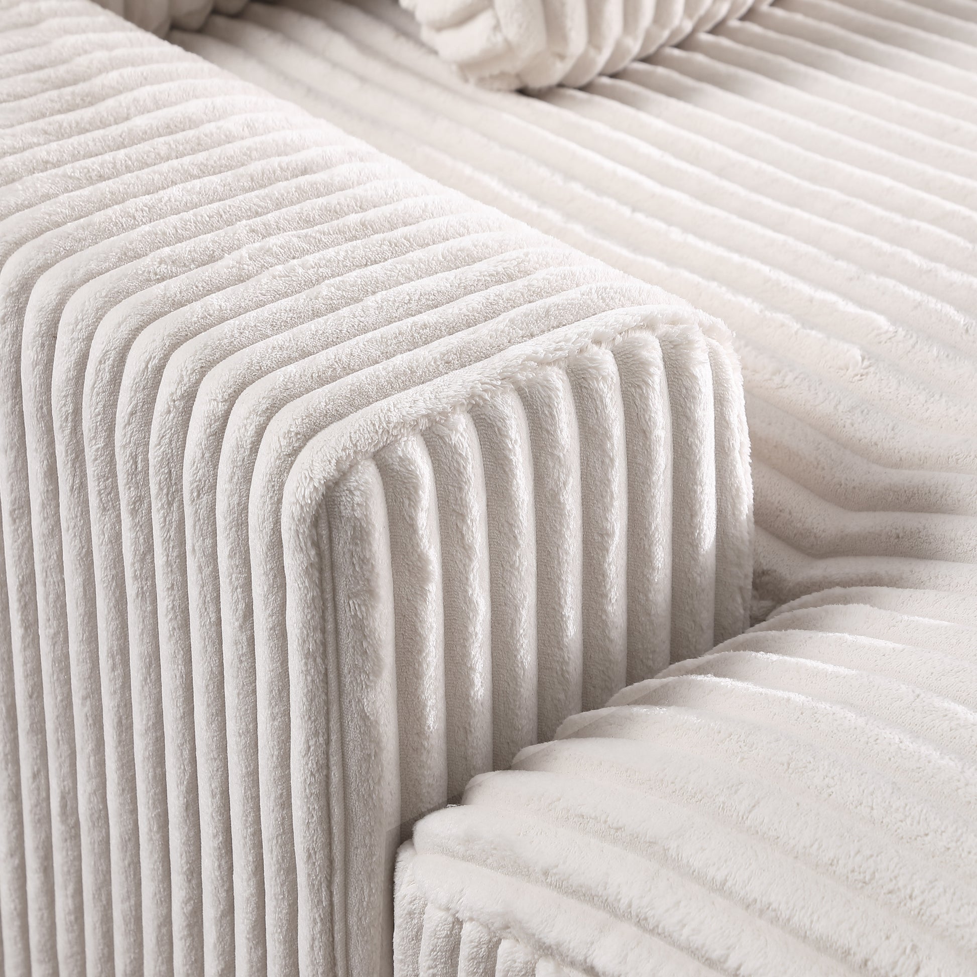 Closeup of soft ivory corduroy fabric texture on a plush sofa armrest