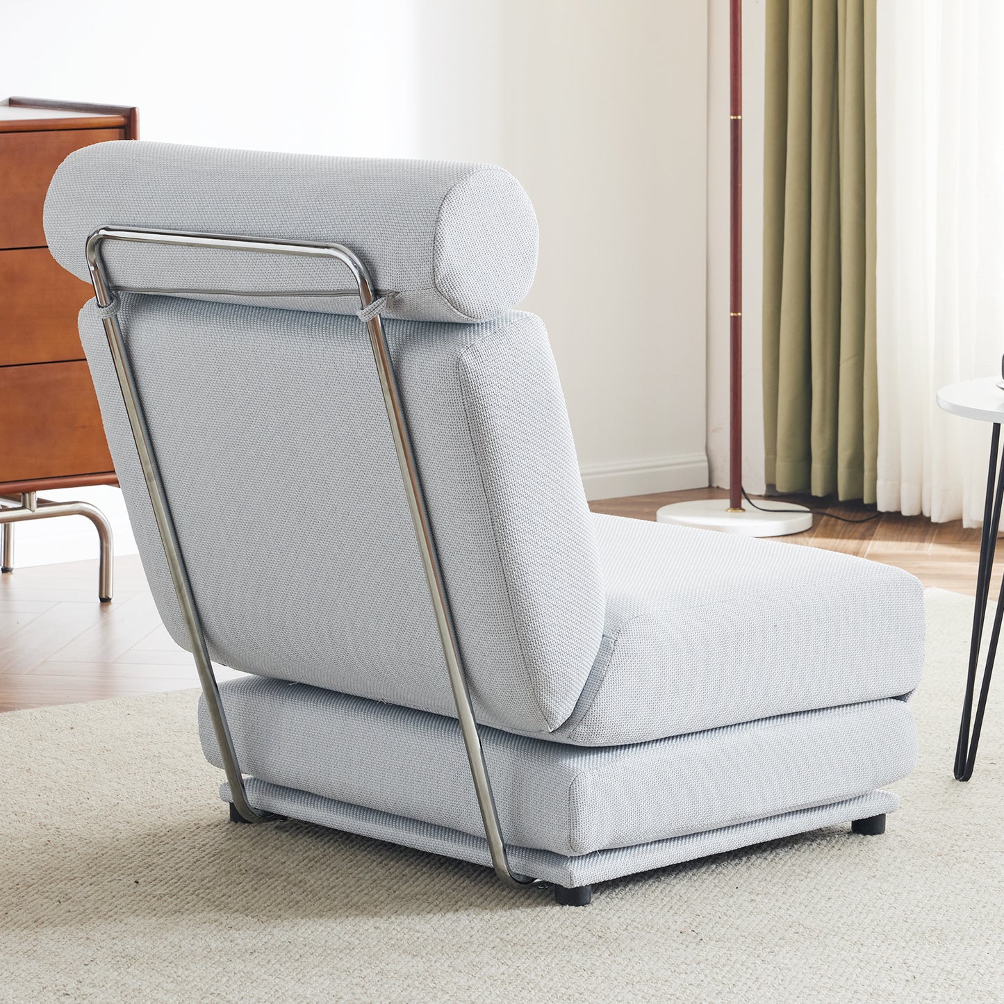 Light gray upholstered armchair with chrome metal frame and adjustable headrest