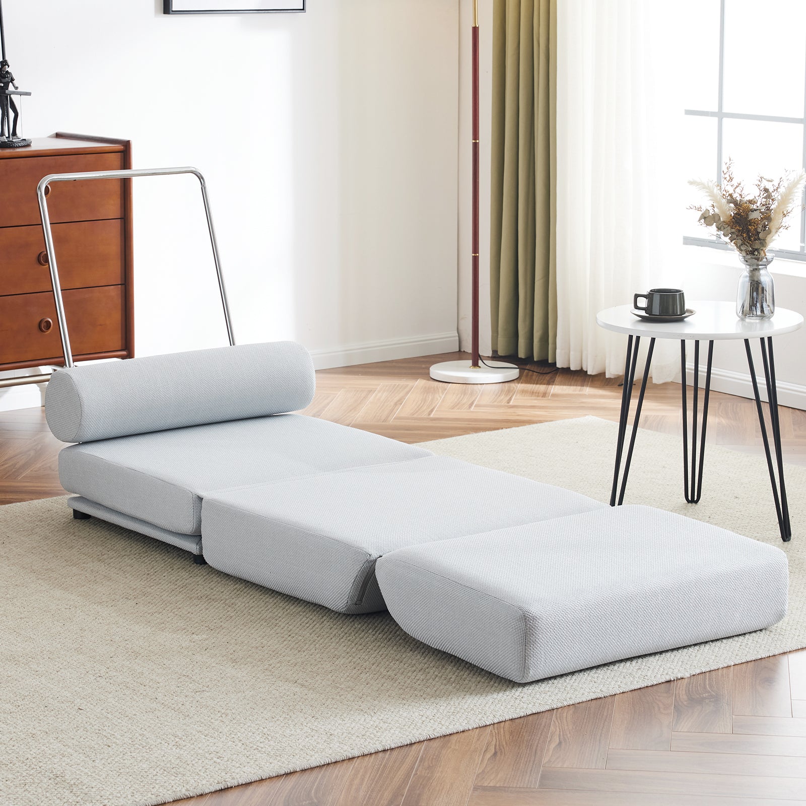 Light grey convertible sofa bed with plush fabric and a cylindrical bolster pillow for modern living