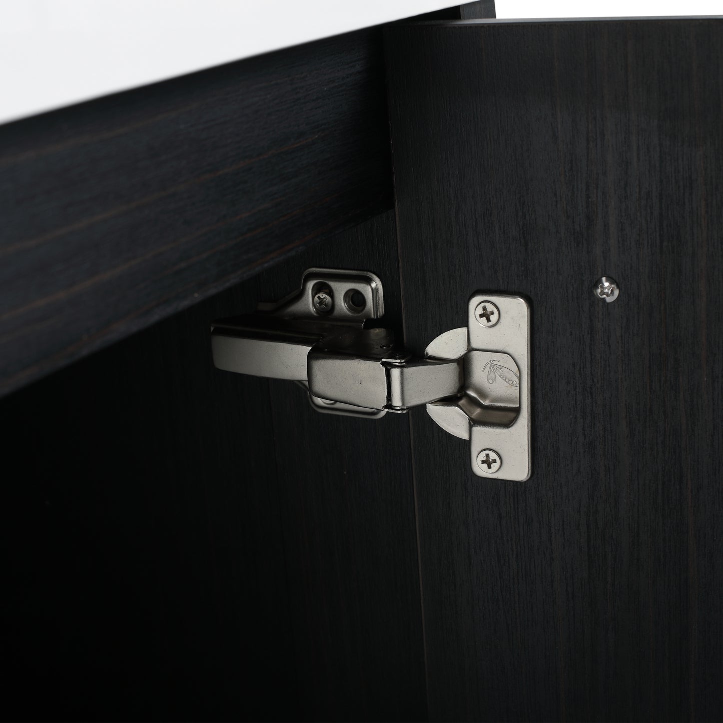 Closeup of a brushed nickel cabinet hinge attached to dark wood cabinet door