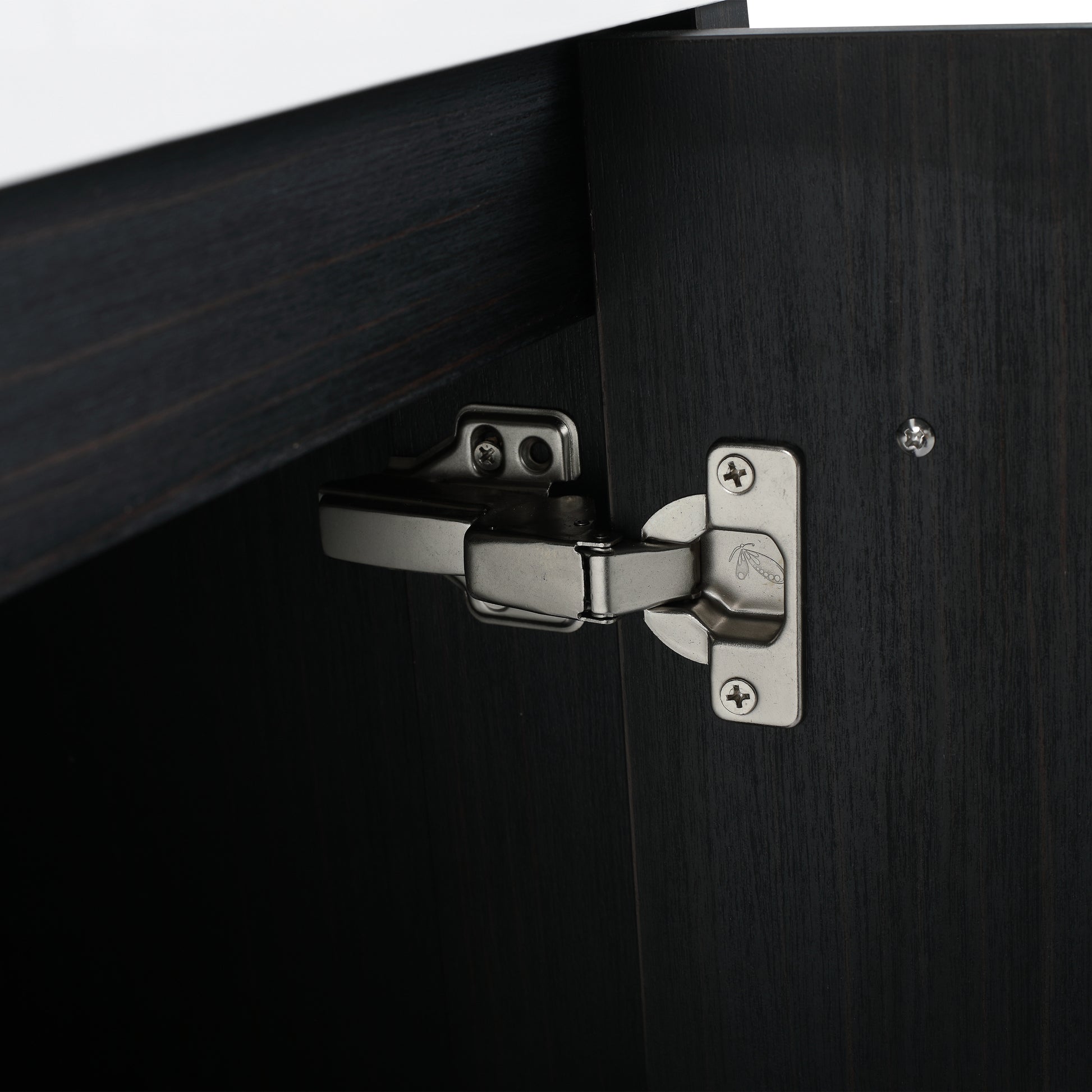Closeup of a brushed nickel cabinet hinge attached to dark wood cabinet door