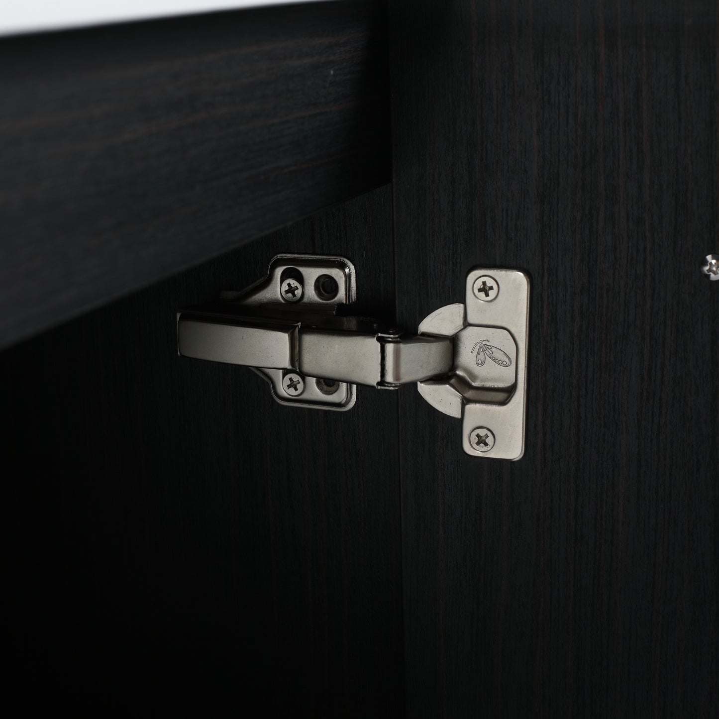 Closeup of a brushed nickel cabinet hinge on dark wood