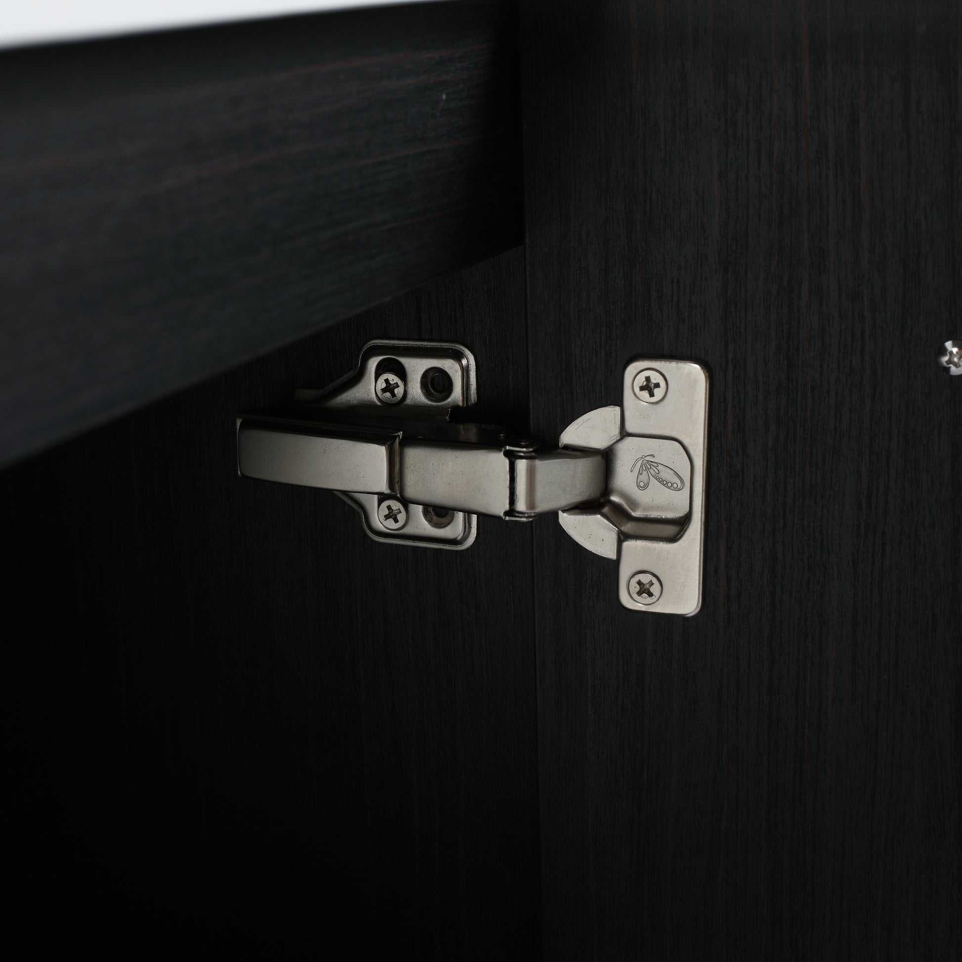 Closeup of a brushed nickel cabinet hinge on dark wood