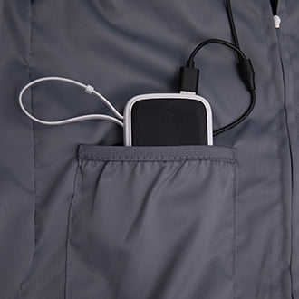 Grey jacket pocket with black power bank and white earbud cable attached