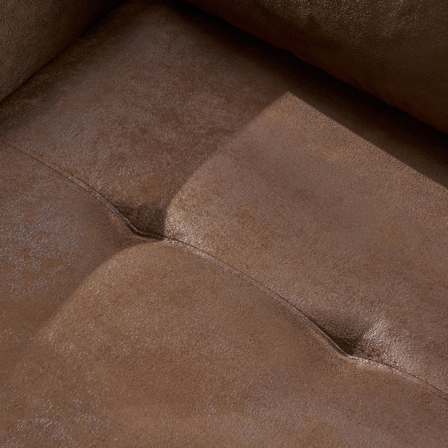 Closeup of rich brown faux leather couch with tufted stitching detail