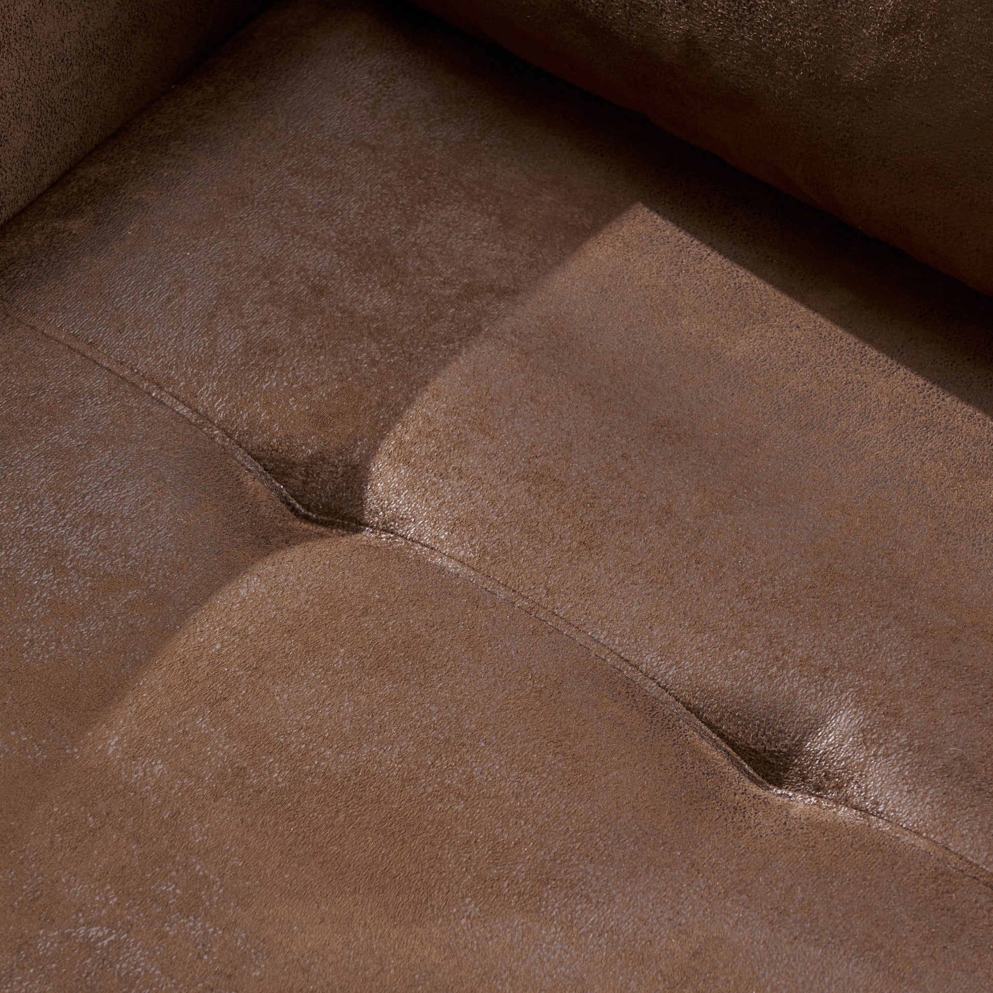 Closeup of rich brown faux leather couch with tufted stitching detail