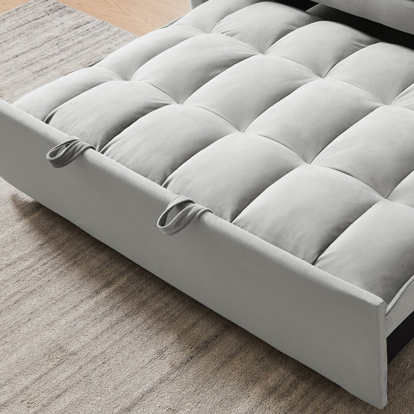 Light gray velvet sofa bed with tufted cushioning and armrest loops
