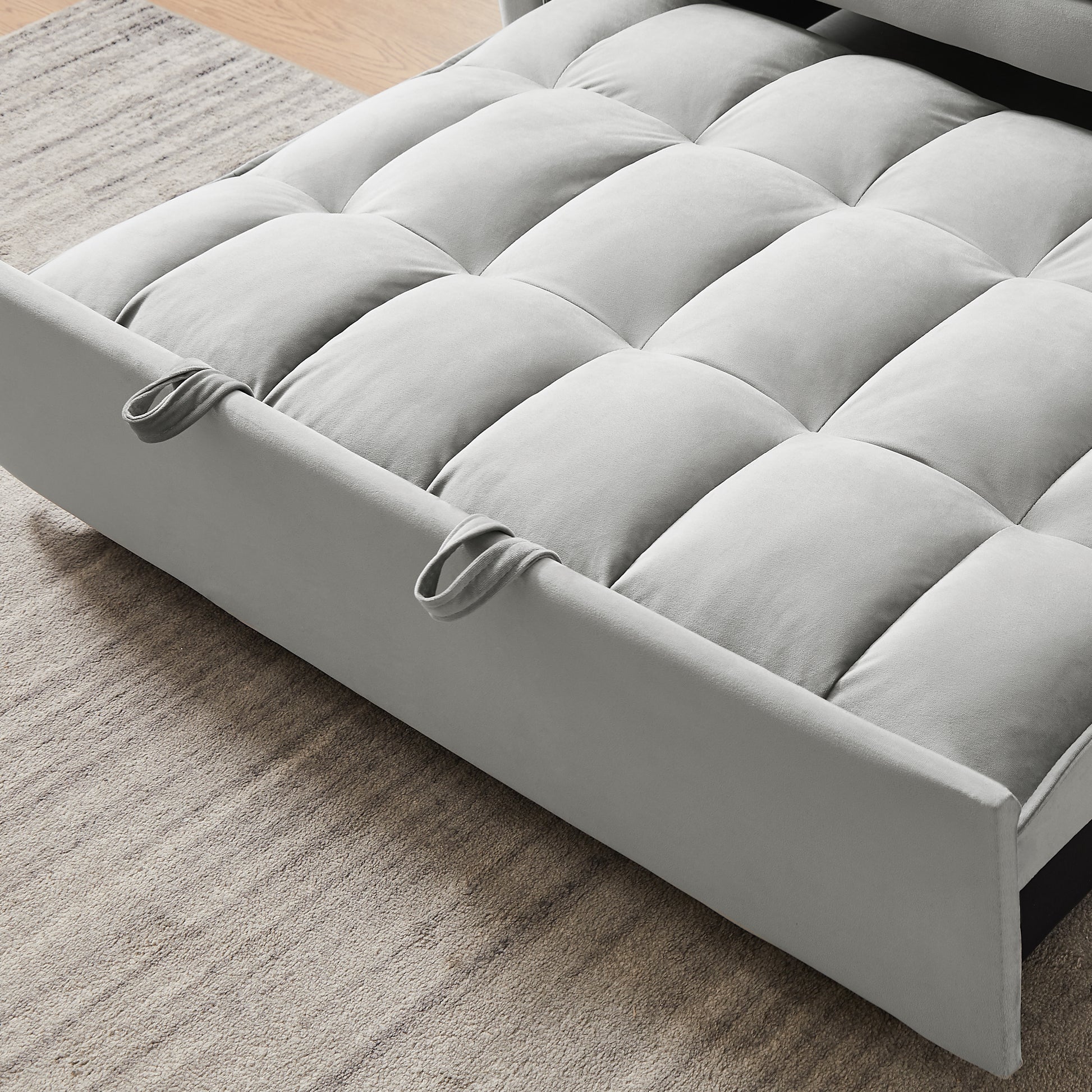 Light gray velvet sofa bed with tufted cushioning and armrest loops