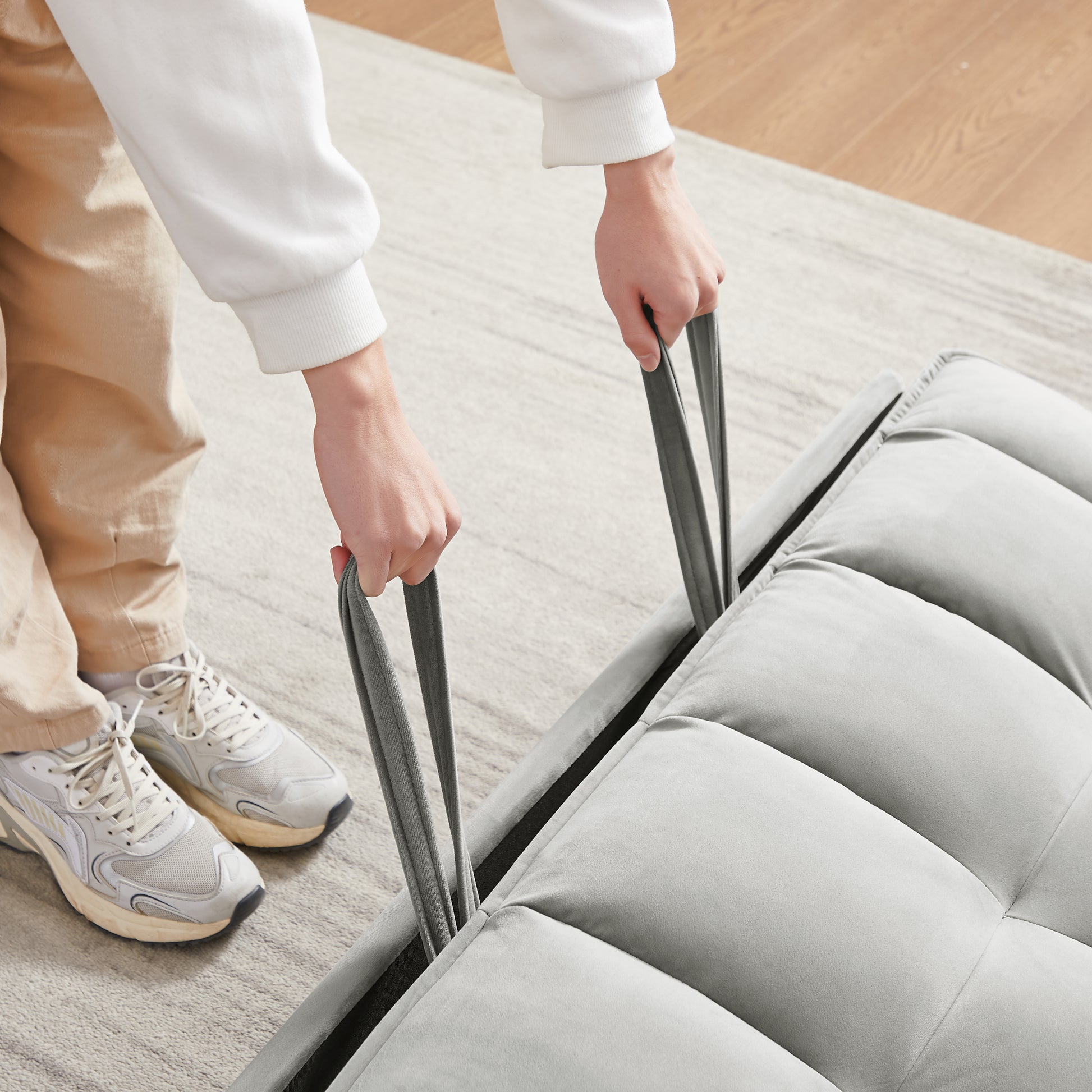 Light grey velvet floor chair with pullup straps for easy transport