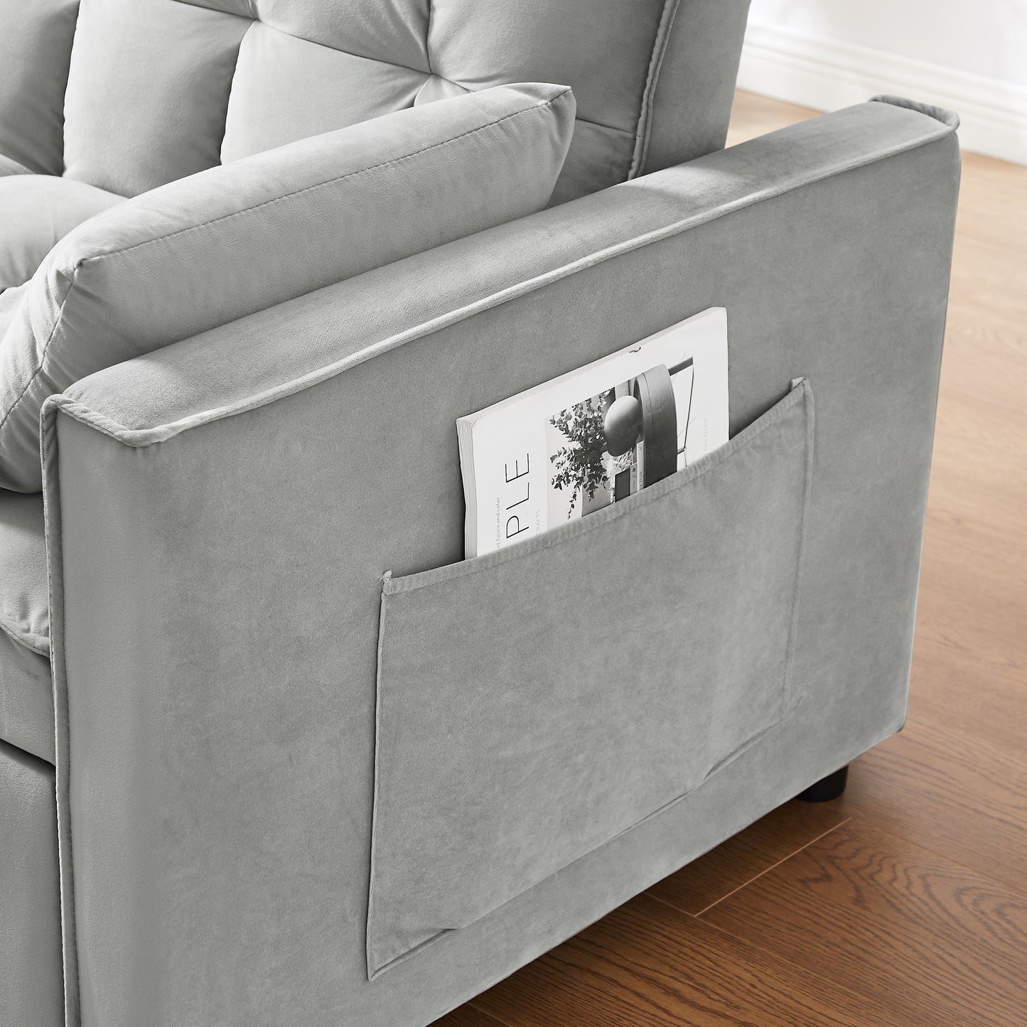 Grey velvet sofa with tufted cushions and integrated side pocket for magazines