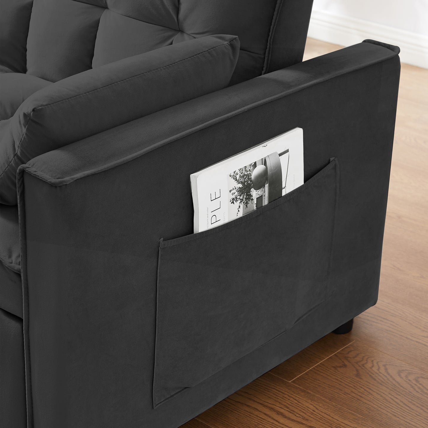 Dark gray velvet sofa armrest with builtin pocket holding a magazine