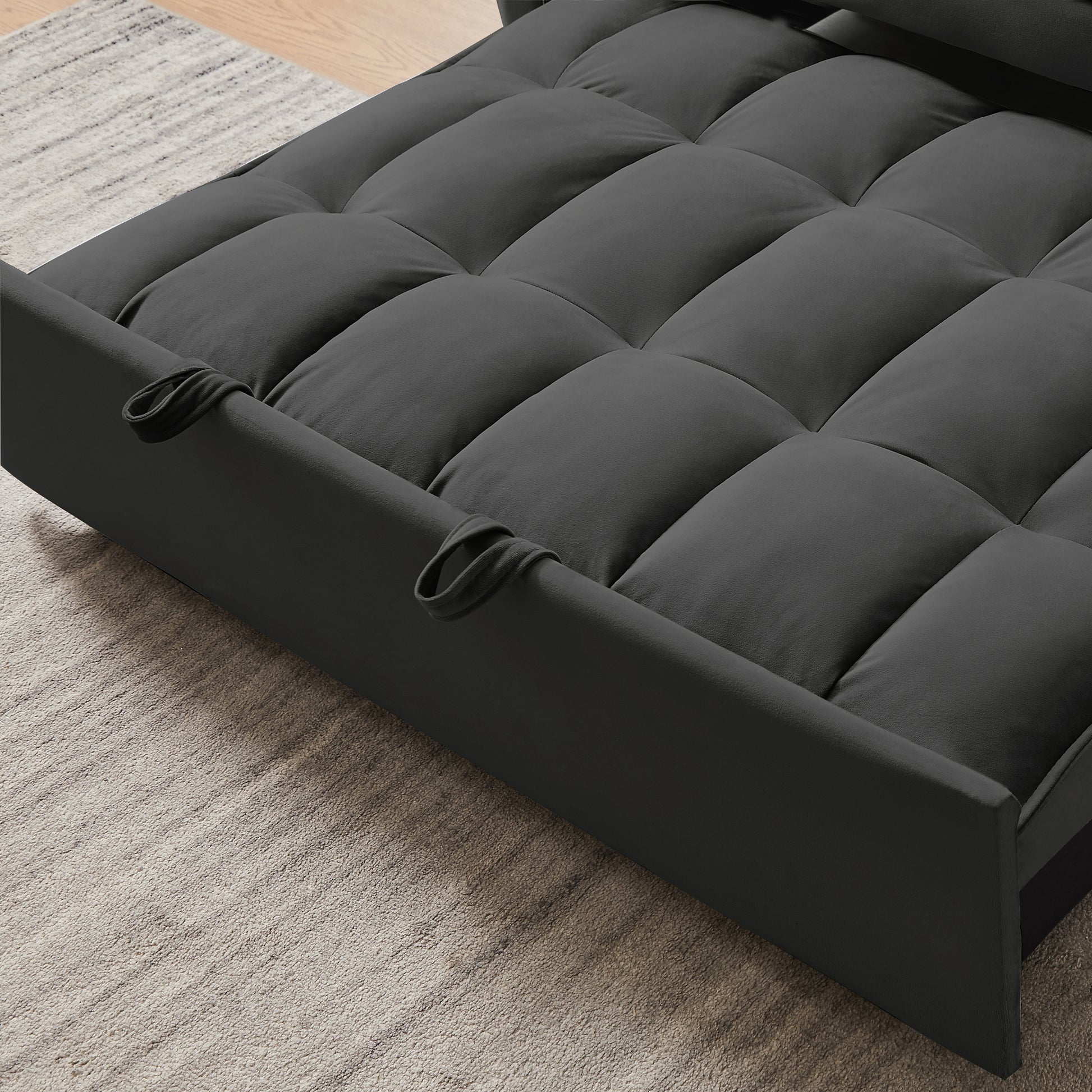 Dark gray tufted futon sofa with plush fabric and integrated armrest loops