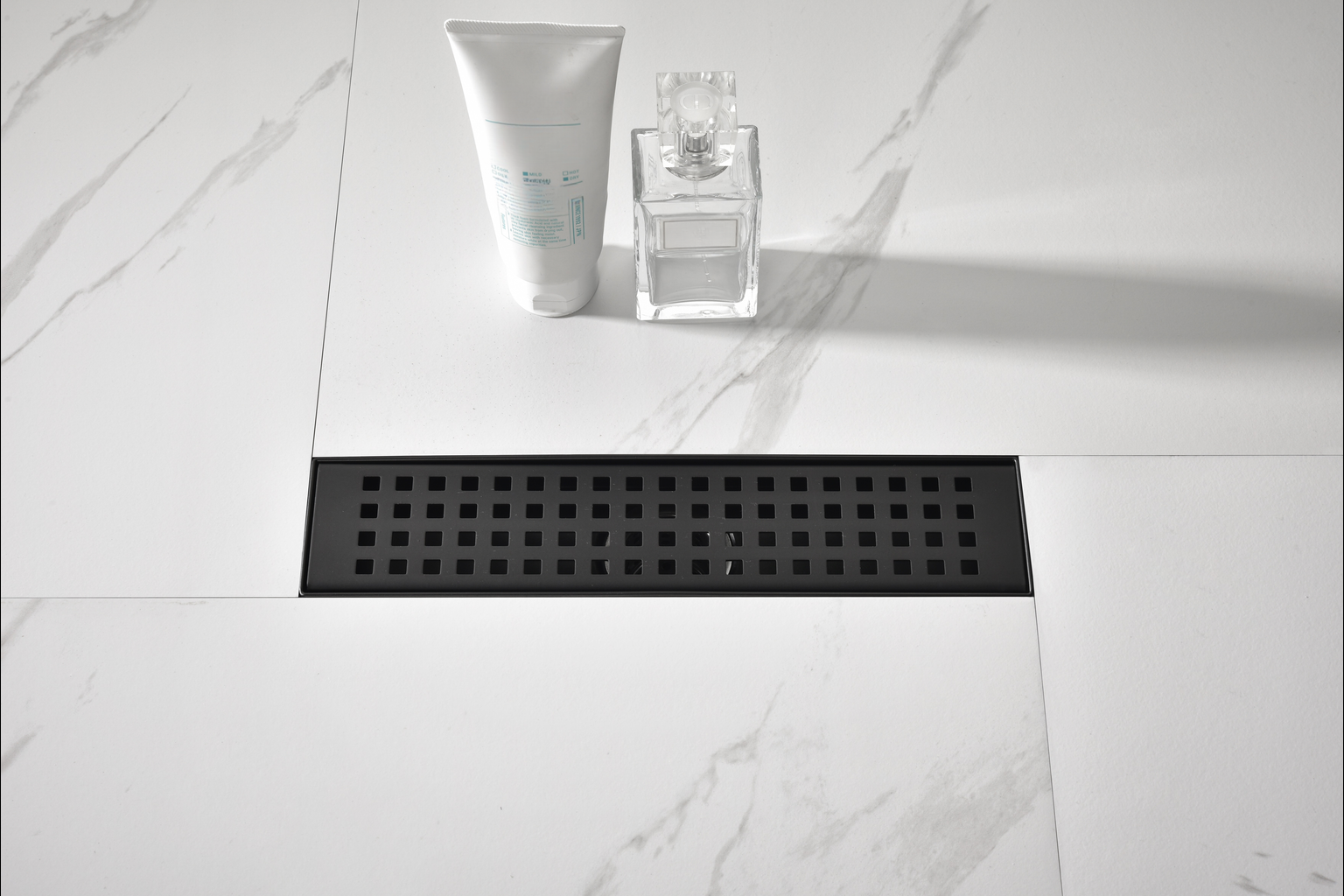 Modern black shower drain with minimalist design on marbleeffect tiles