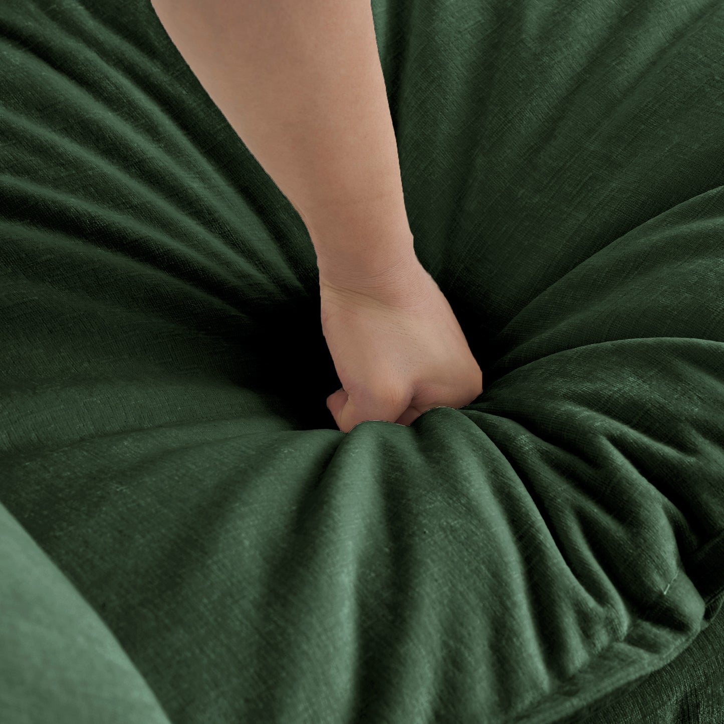 Hand pressing into plush forest green velvet fabric showing deep cushioning and softness