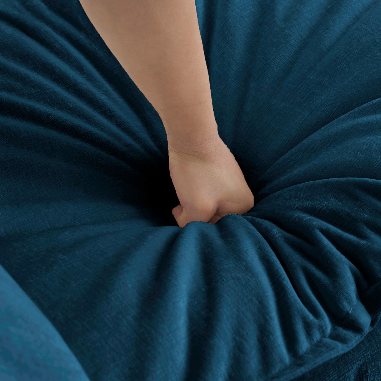 Hand sinking into soft teal velvet fabric highlighting plush texture for upholstery