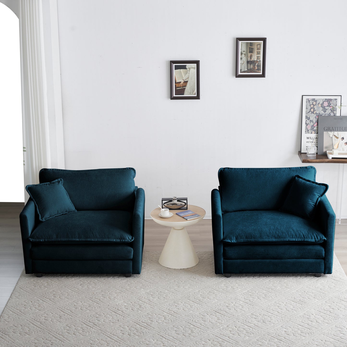 Two plush teal velvet armchairs with accent pillows provide comfortable seating