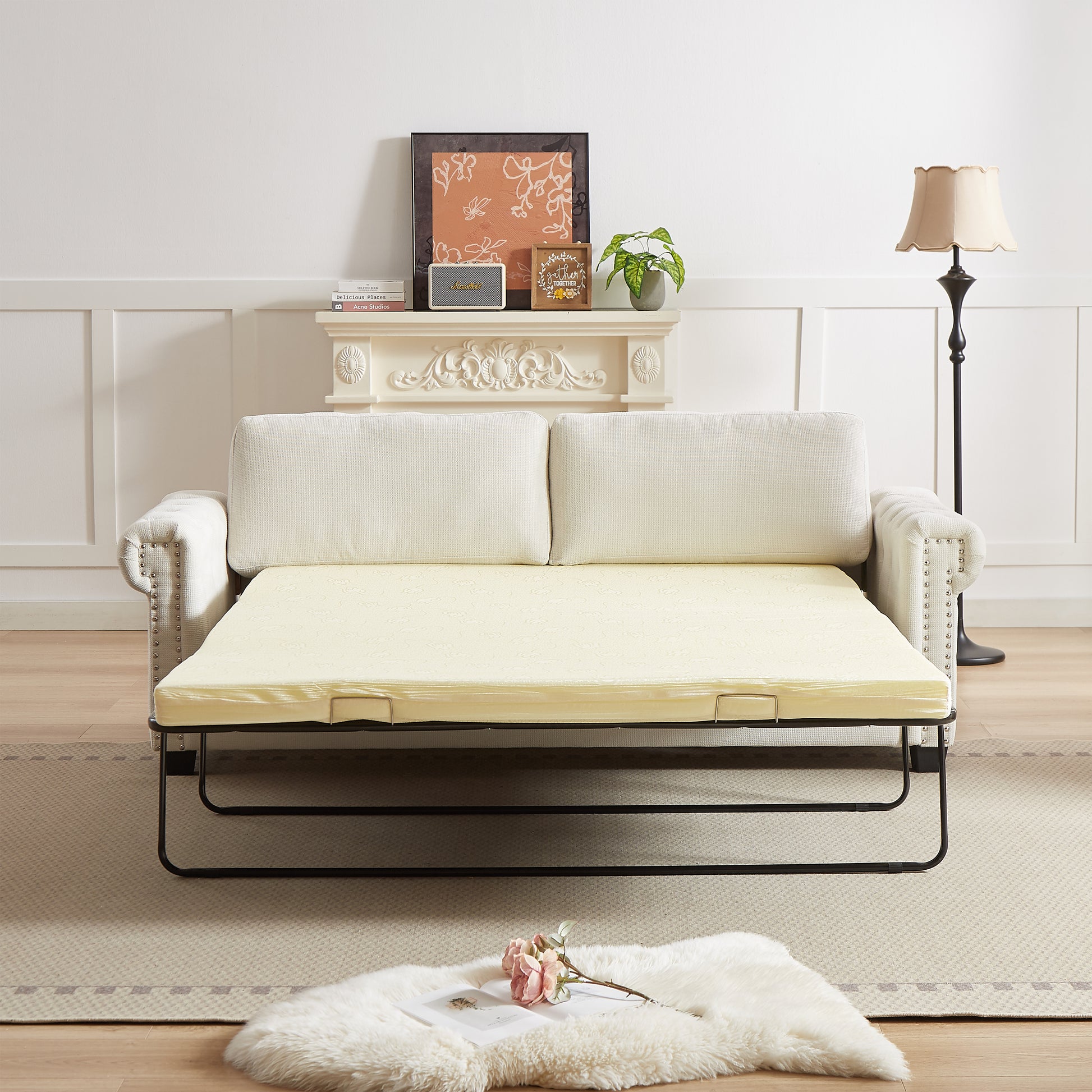 Cream upholstered convertible sofa bed with gold accents unfolded into a bed