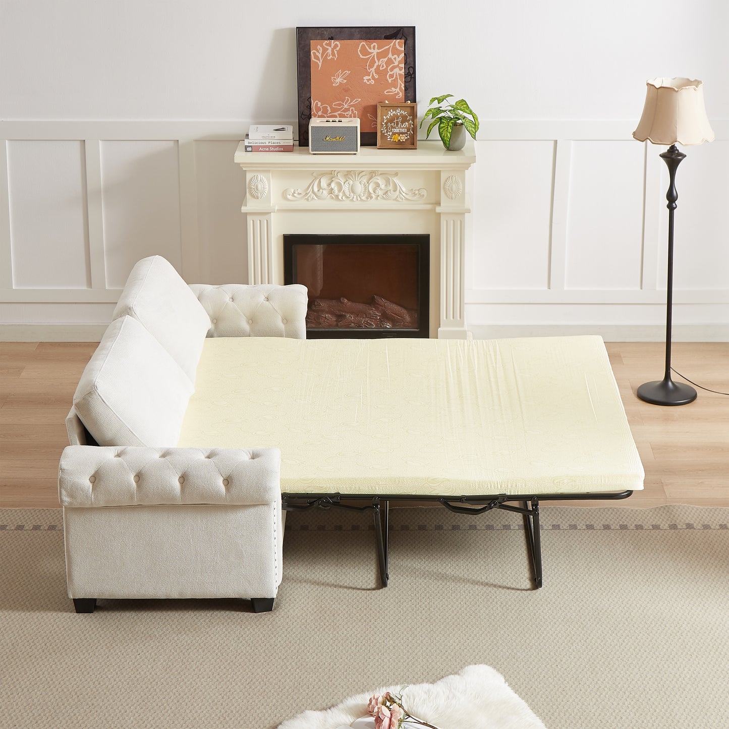 Cream upholstered tufted sofa bed pulled out with a light yellow patterned mattress