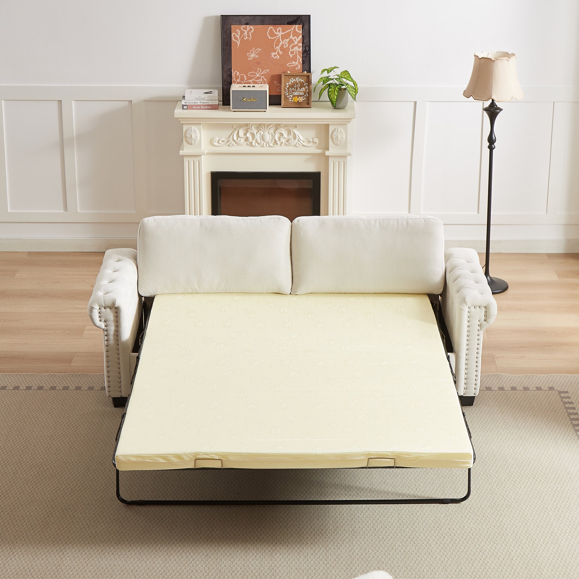 Tufted cream sofa bed with upholstered arms featuring a decorative nailhead trim perfect for guest rooms