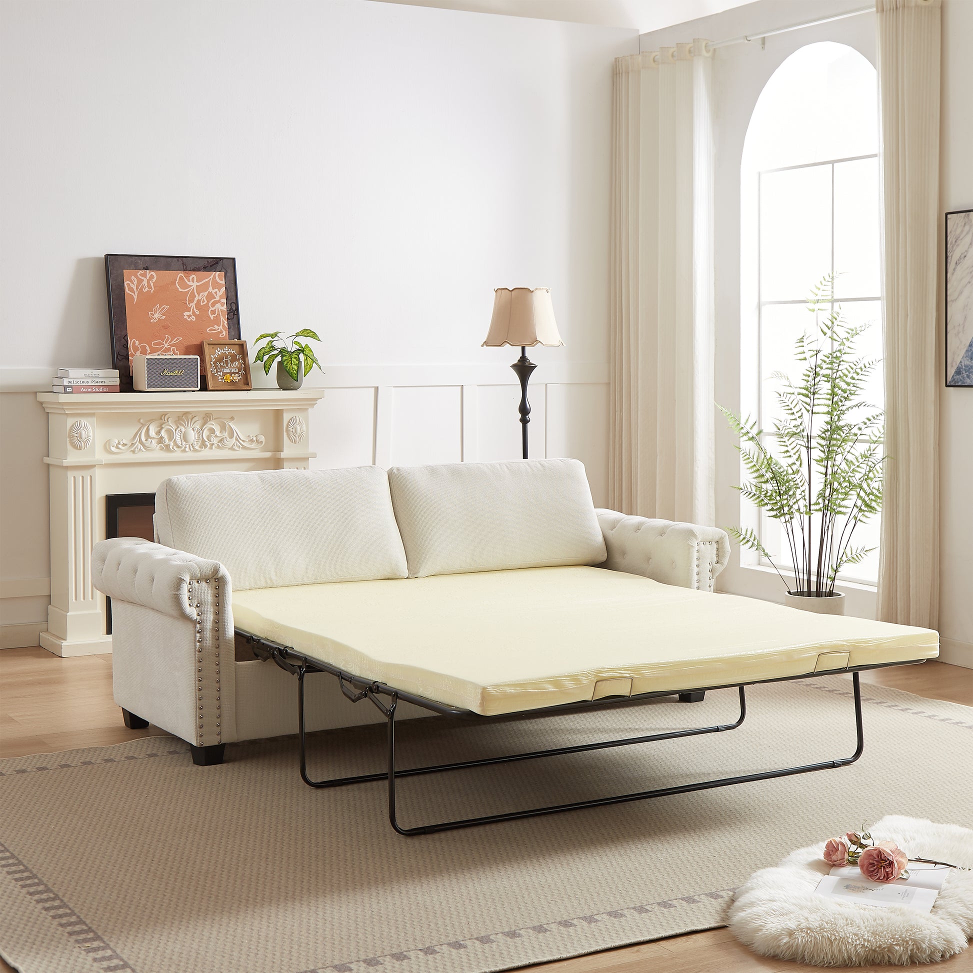 Cream chesterfield sofa bed with tufted arms pulled out to reveal a pale yellow mattress