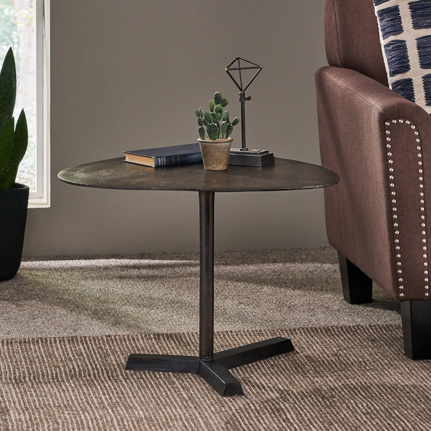 Round metal end table with dark distressed finish and pedestal base