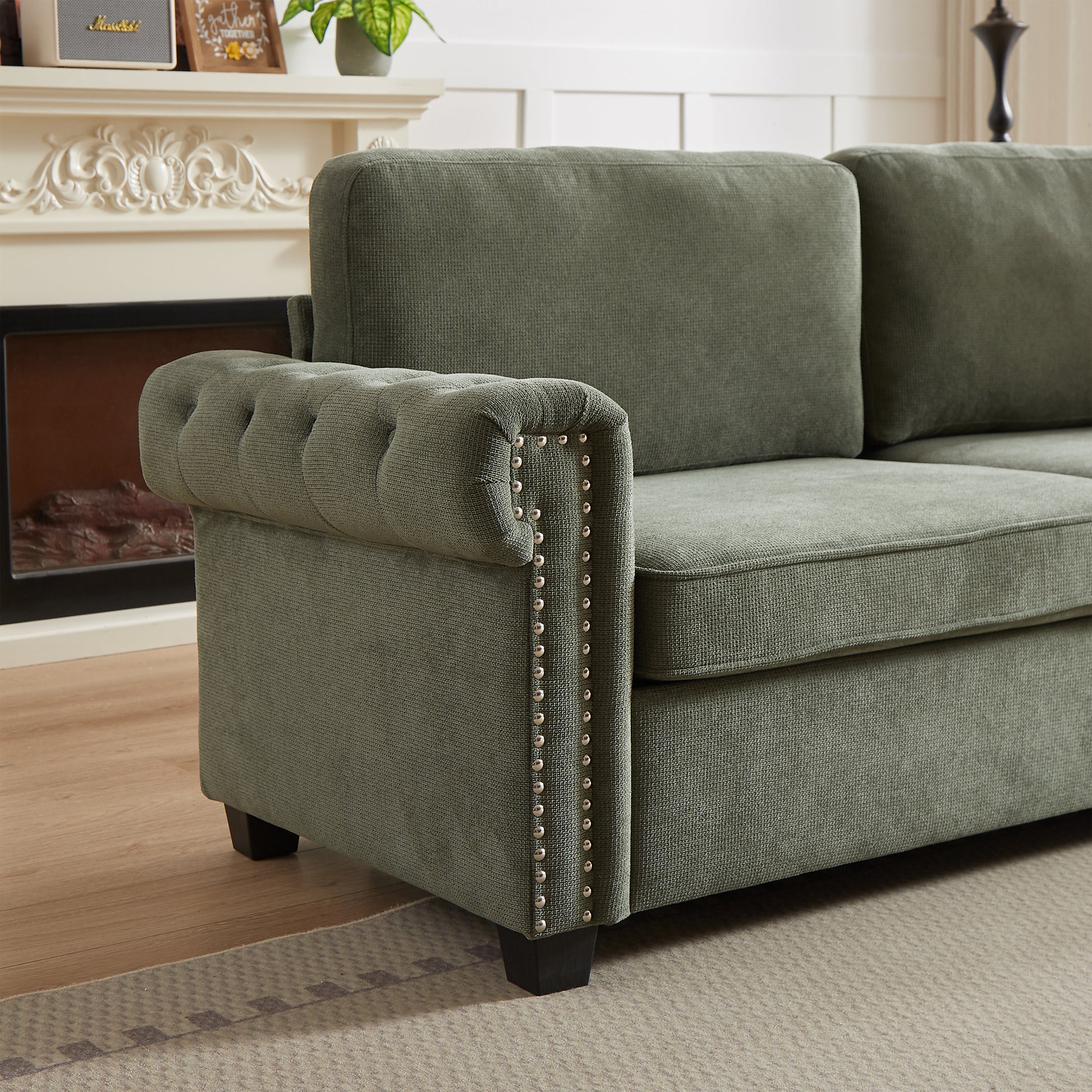 Green fabric sofa with tufted armrest and nailhead trim detailing