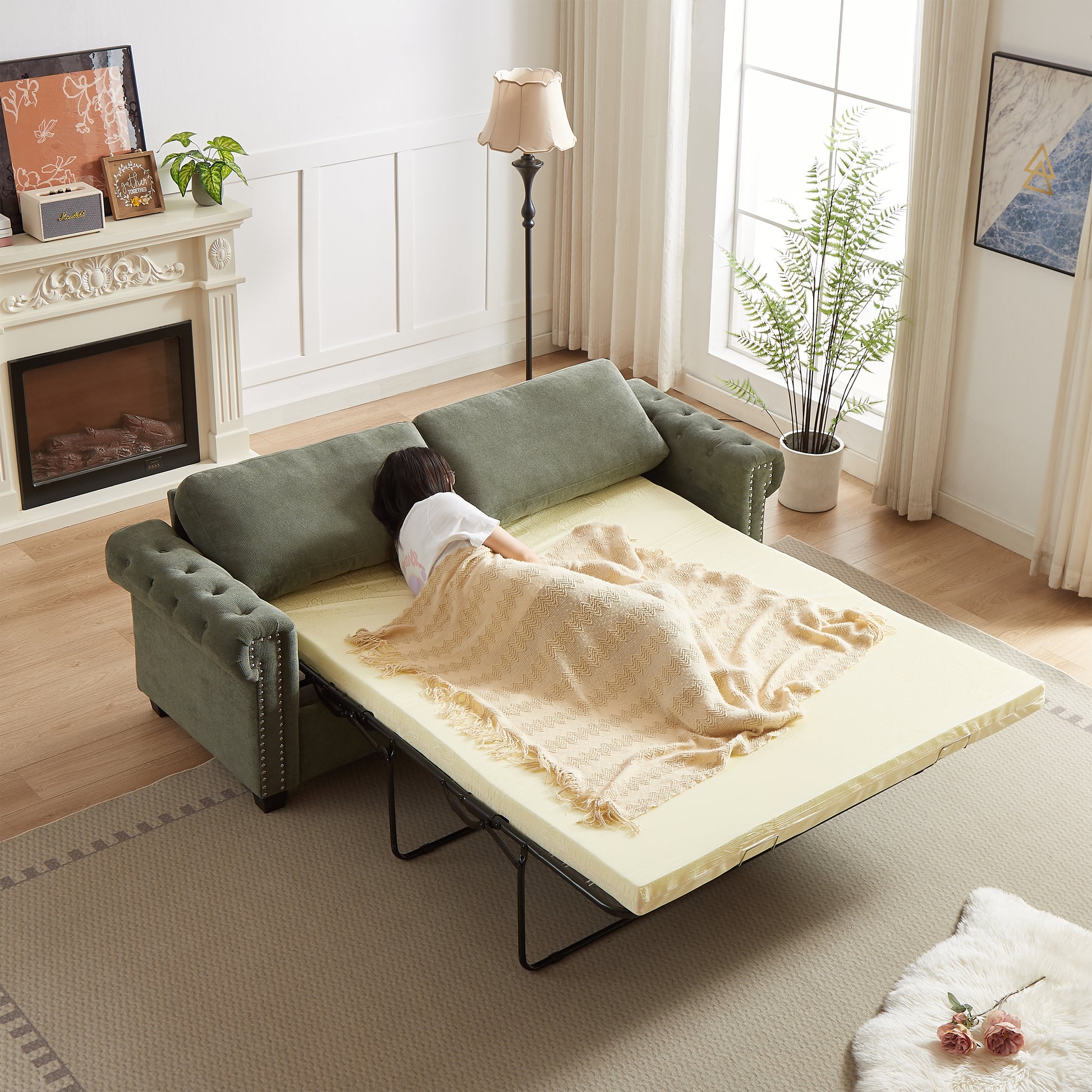 Green velvet sleeper sofa with tufted arms and studded trim featuring a pullout bed