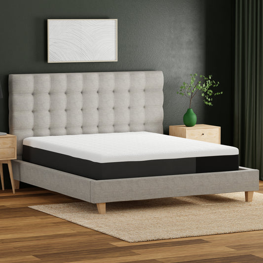 Queen size memory foam mattress with a white quilted top and black base on a grey upholstered bed frame