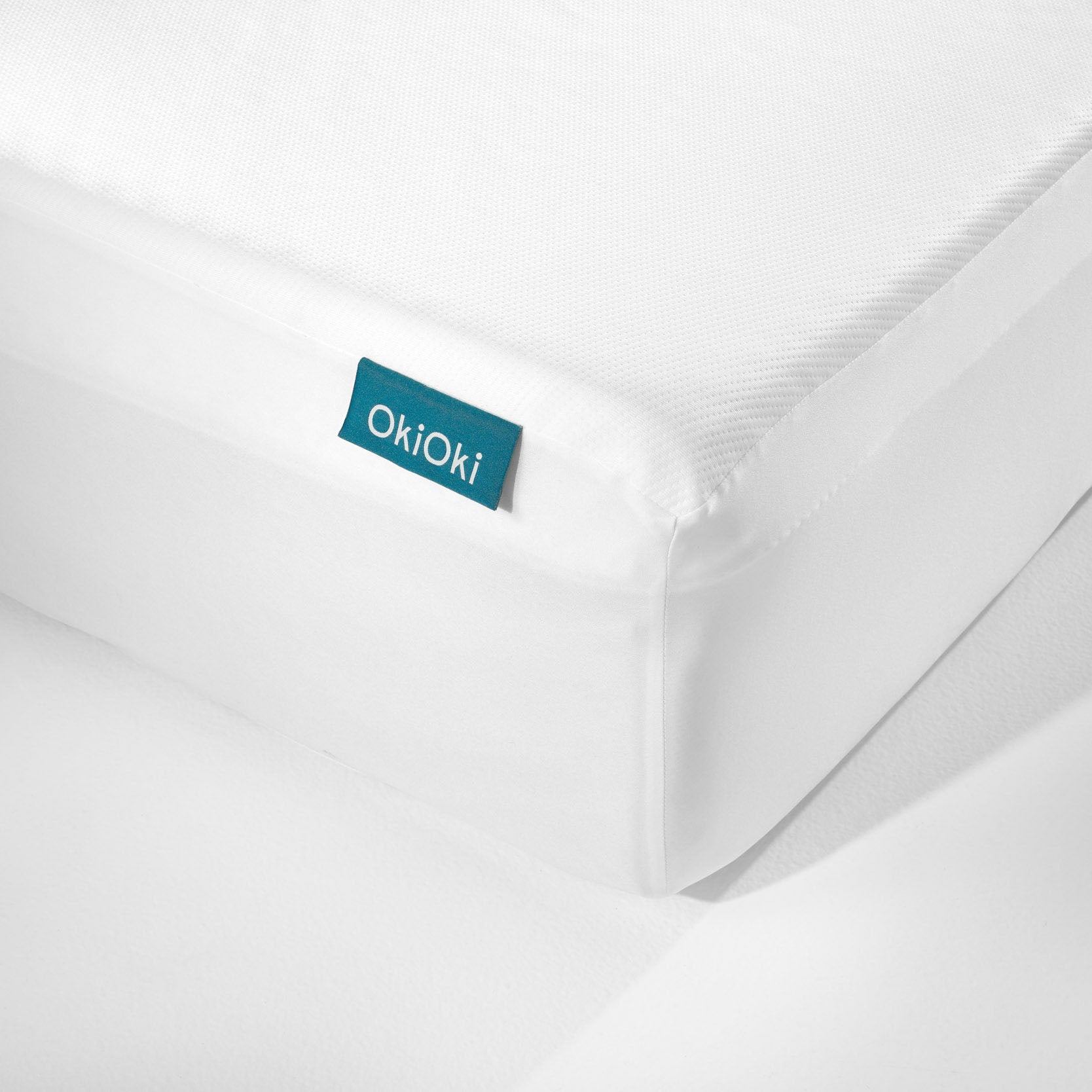 White OkiOki mattress protector with textured surface and blue tag