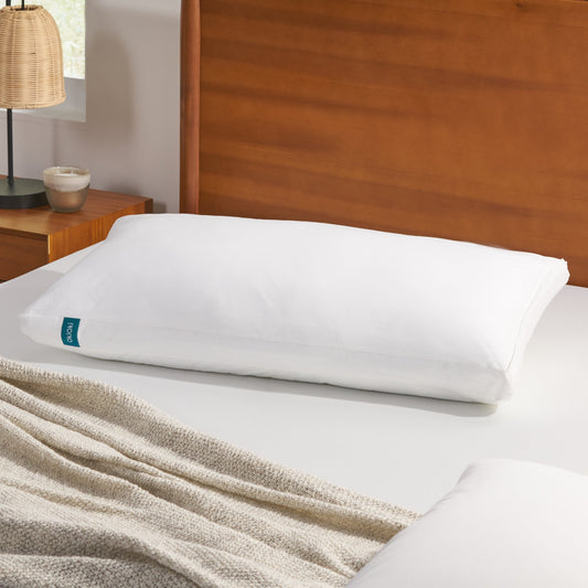White cotton bed pillow with teal tag on a white bed
