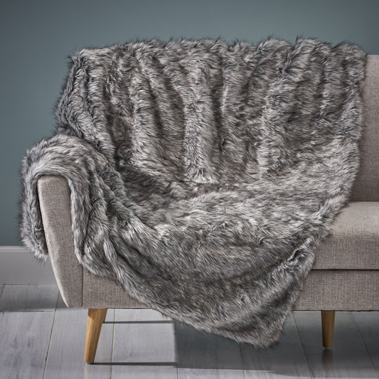 Plush grey faux fur throw blanket draped over a modern sofa adding cozy texture