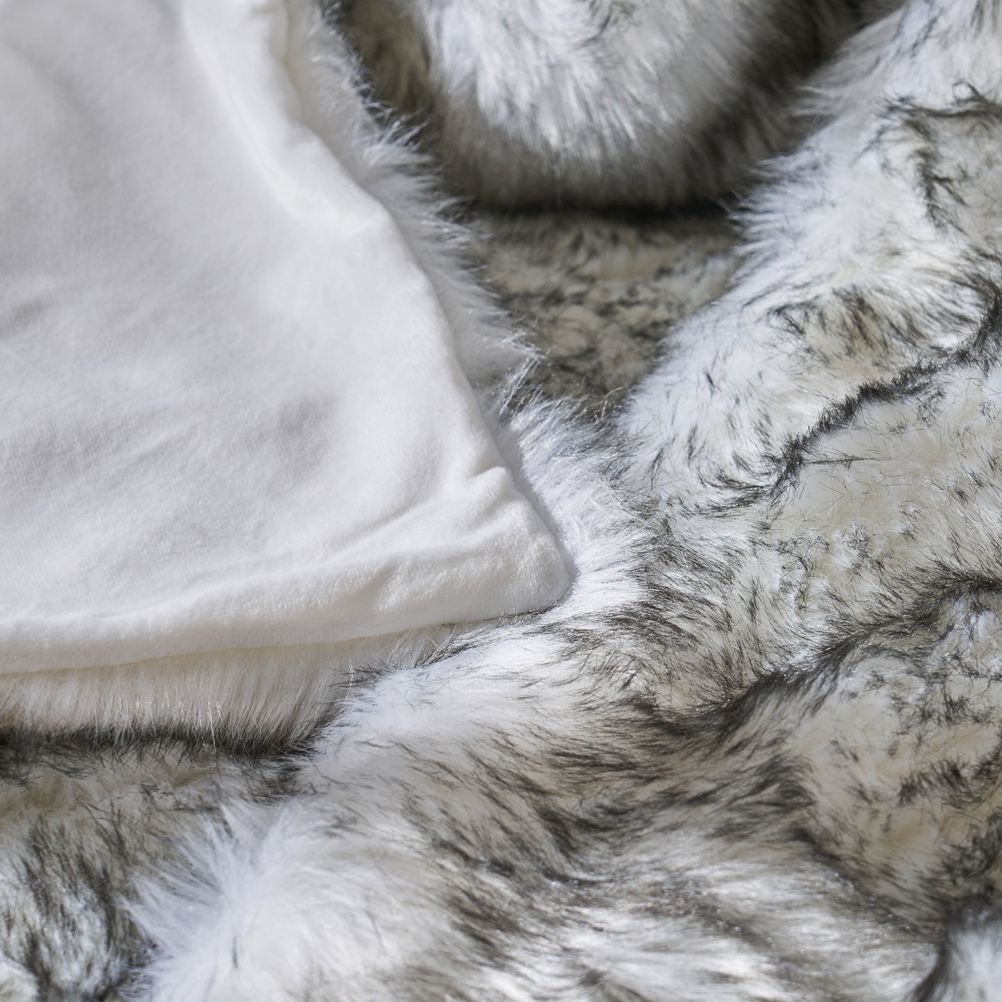 Close up of soft white tshirt draped over luxurious grey and white faux fur throw