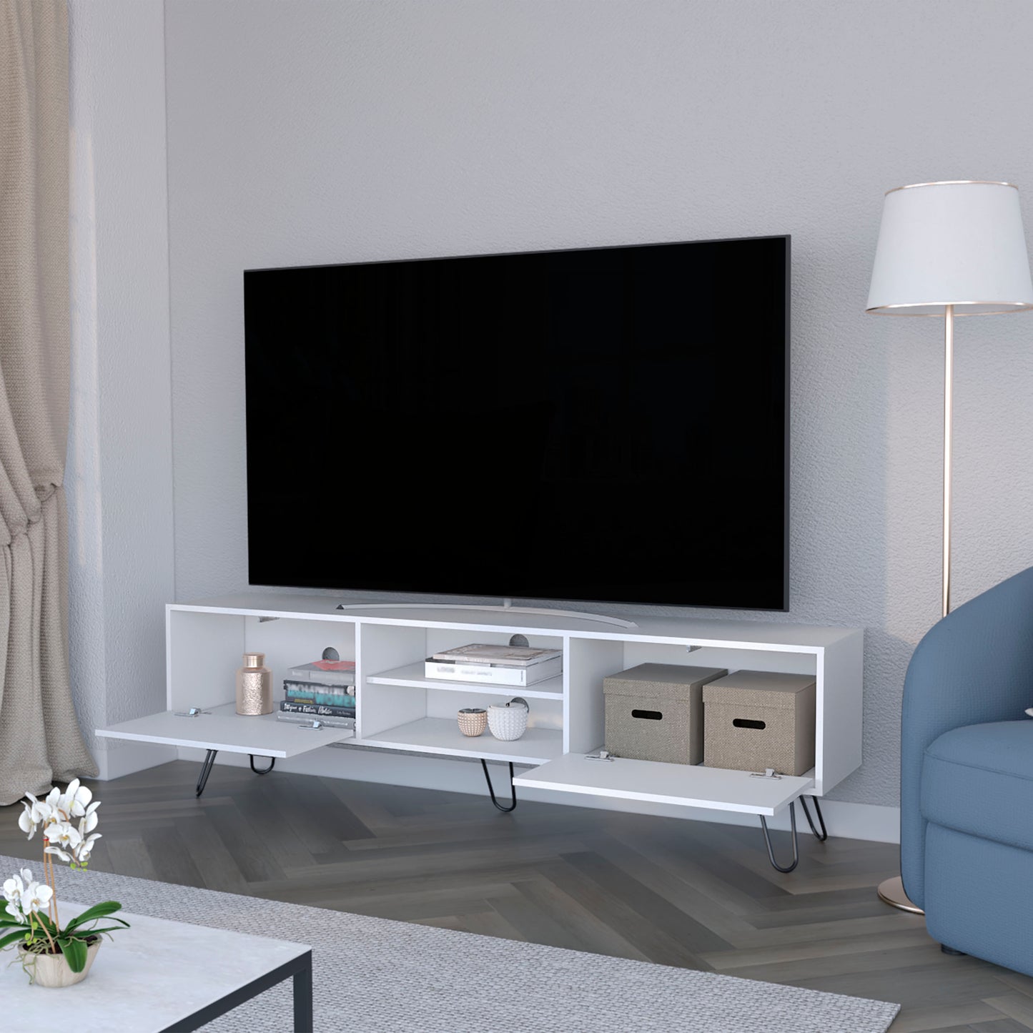 Modern white media console with angled legs and open shelving holding books and decor