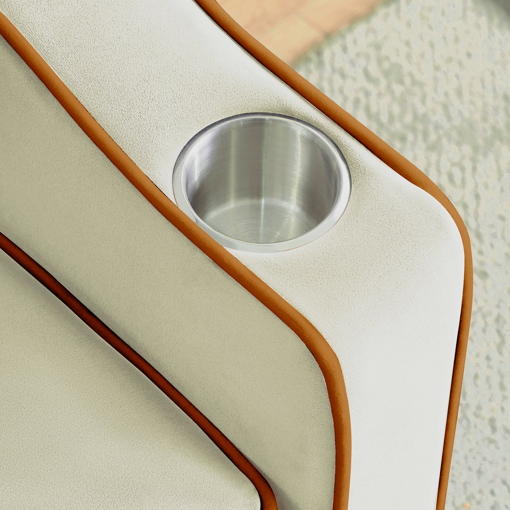 Cream fabric sofa with brown piping and a stainless steel cup holder