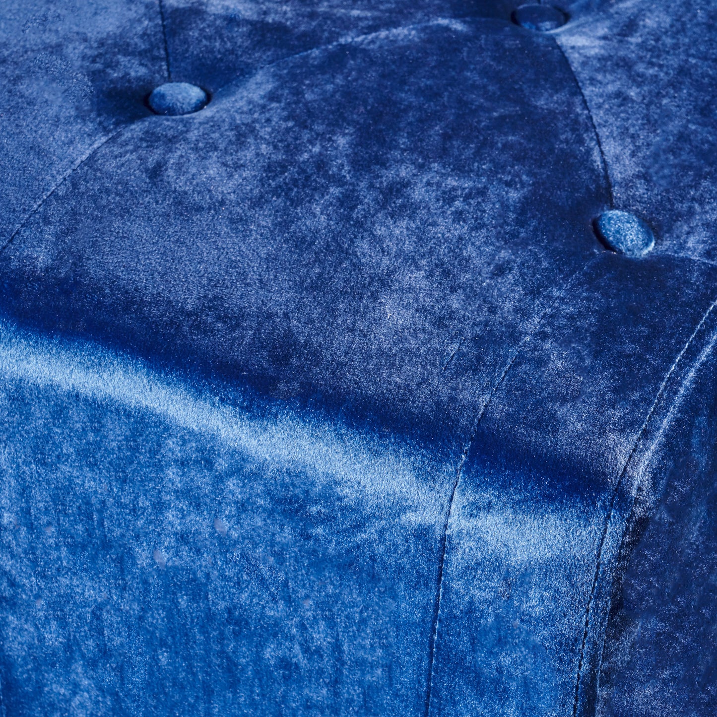 Closeup of a luxurious sapphire blue velvet fabric with tufted button accents ideal for upholstery