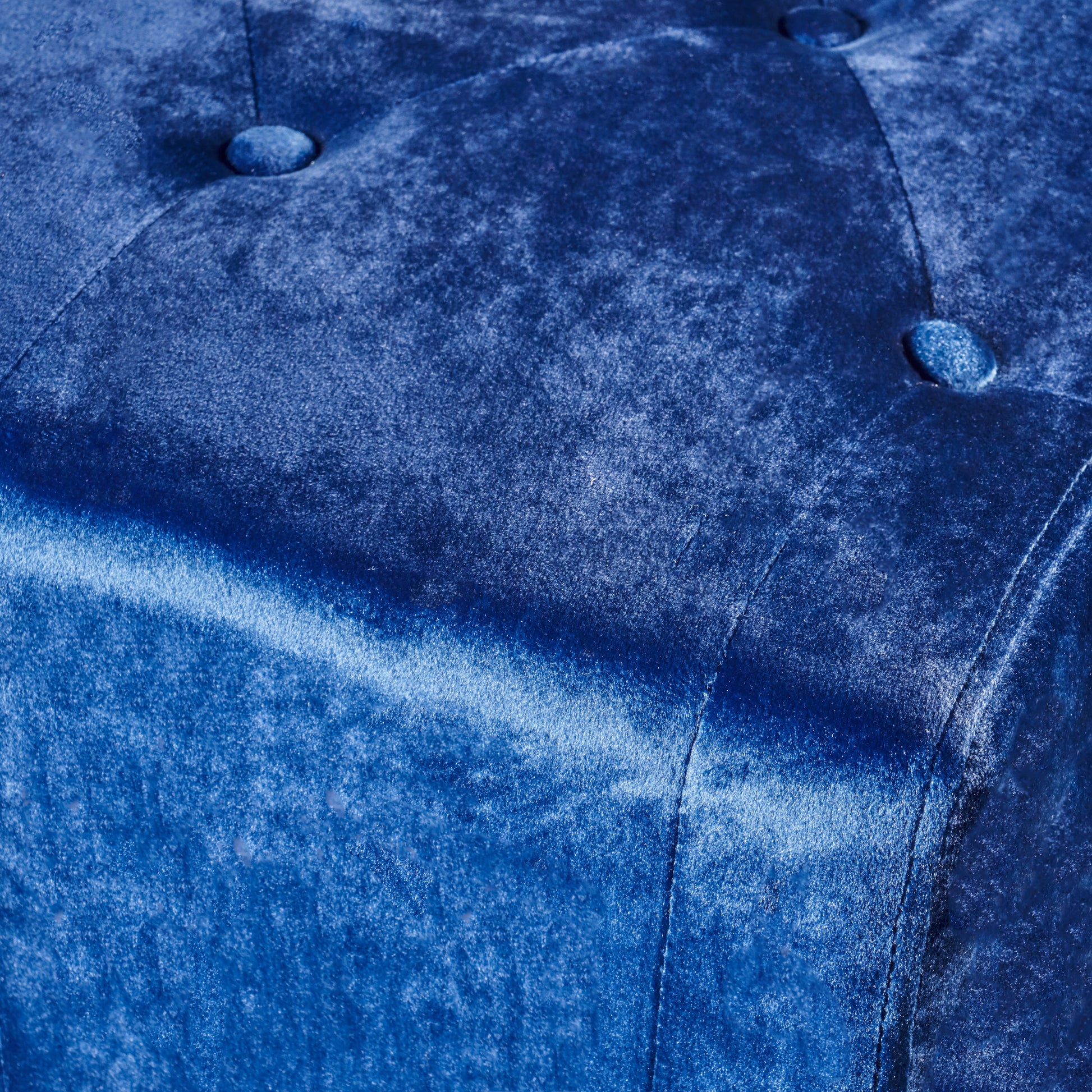 Closeup of a luxurious sapphire blue velvet fabric with tufted button accents ideal for upholstery