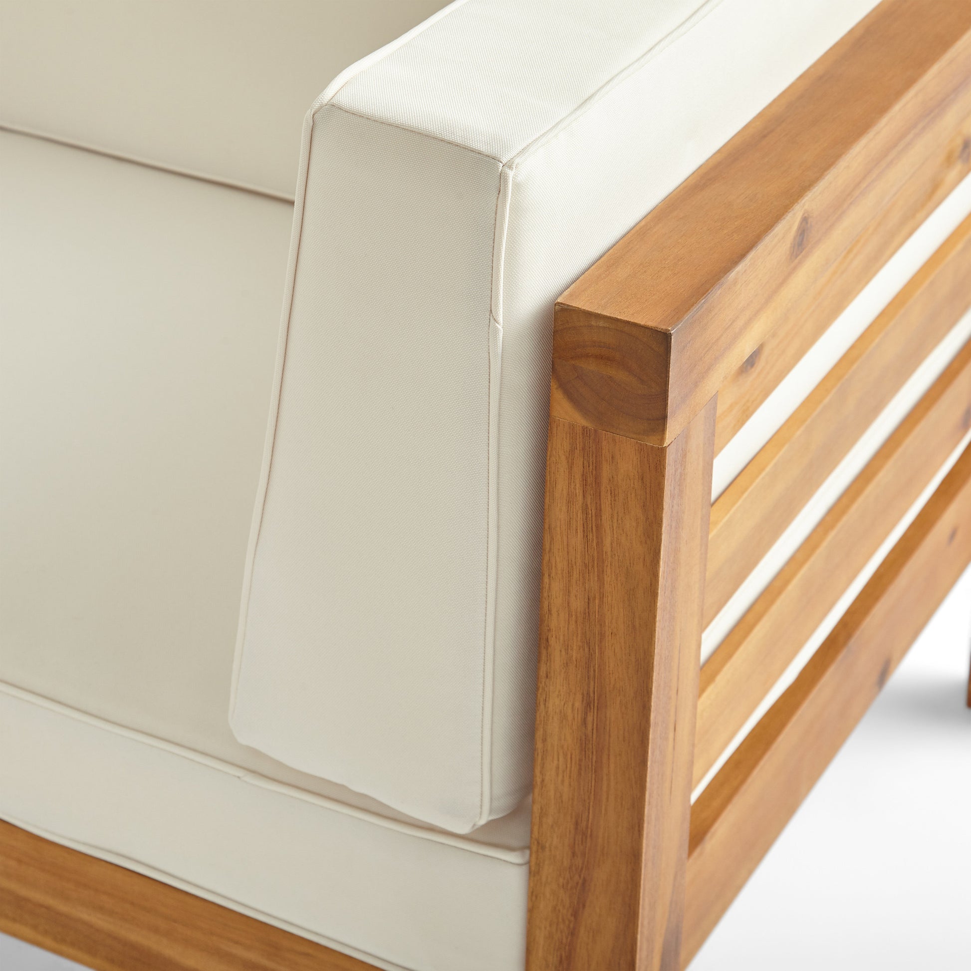 Closeup of a modern teak wood outdoor armchair with cream cushions