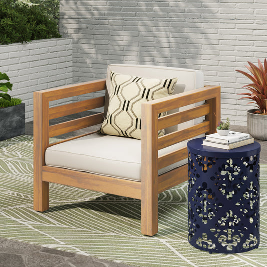 Wooden armchair with cream cushions and a patterned pillow on a patio