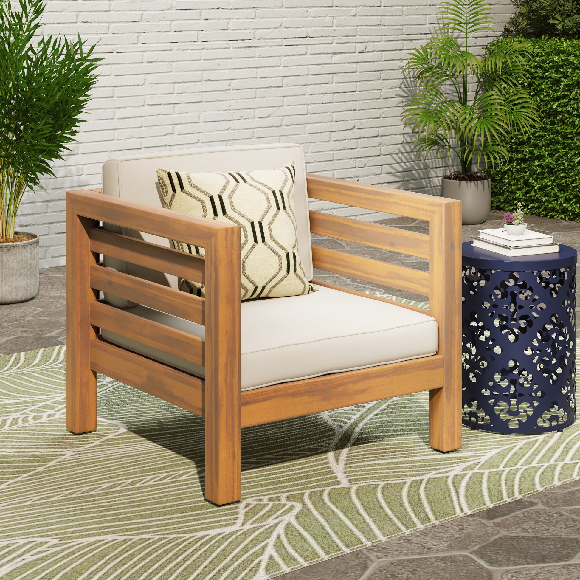 Acacia wood outdoor armchair with cream cushions and patterned pillow