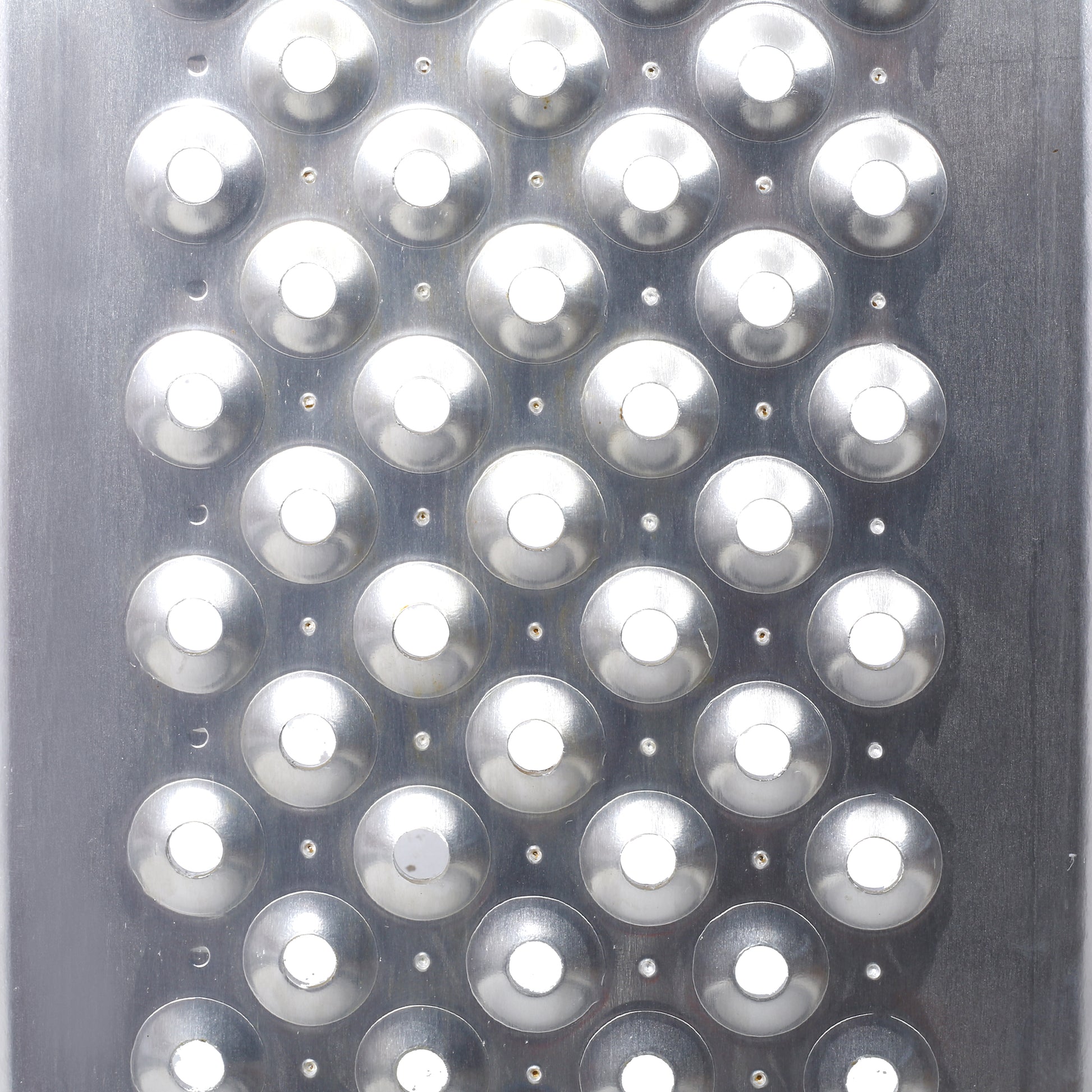 Closeup of a shiny metal grater surface with circular grating holes for food preparation