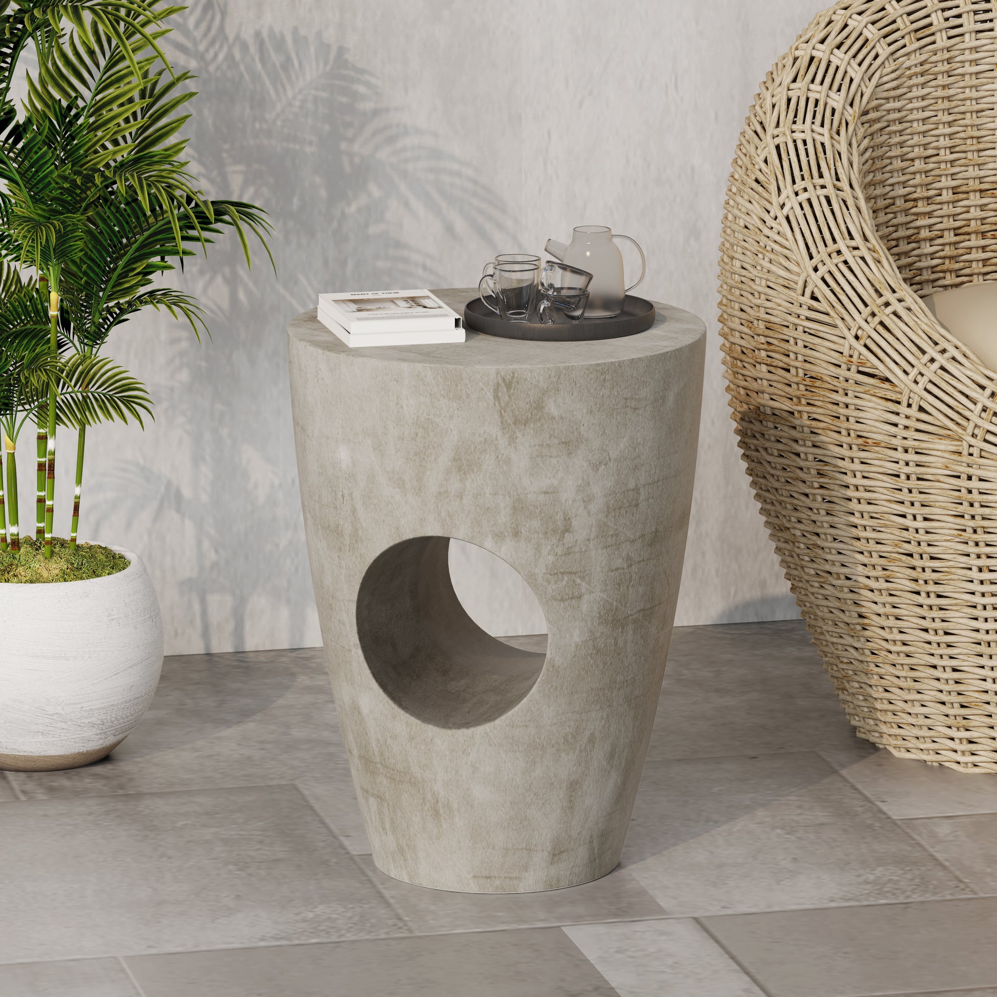 Concrete side table with cutout detail and a book teacups and teapot on top