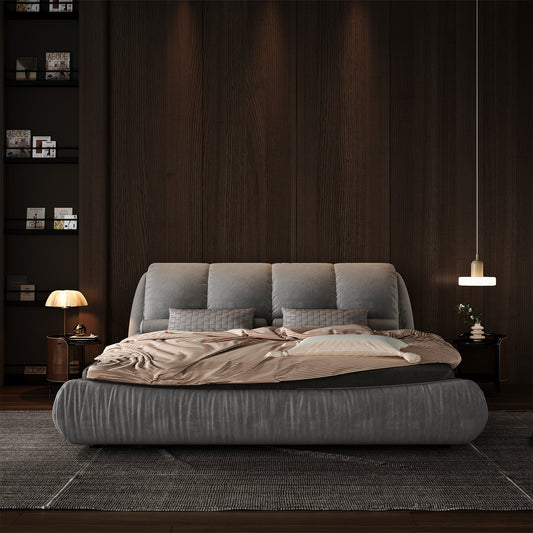 Plush grey upholstered bed with textured grey throw pillows and a striped duvet