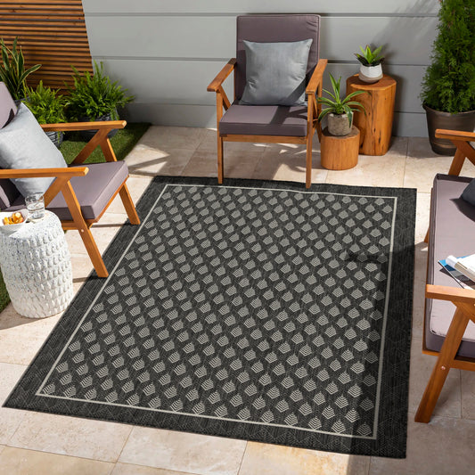 Dark grey outdoor rug with a repeating diamond pattern in light grey and white