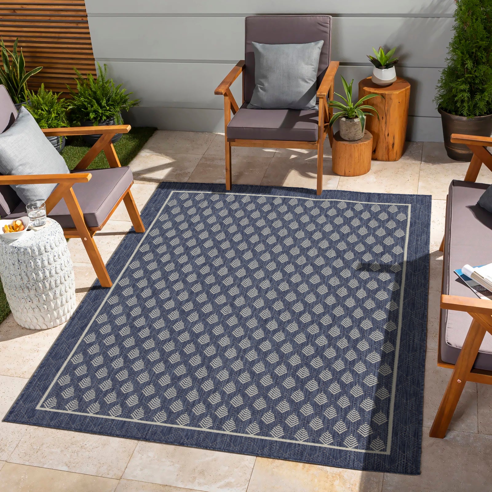 Navy blue outdoor rug with a repeating geometric diamond pattern in a light beige hue