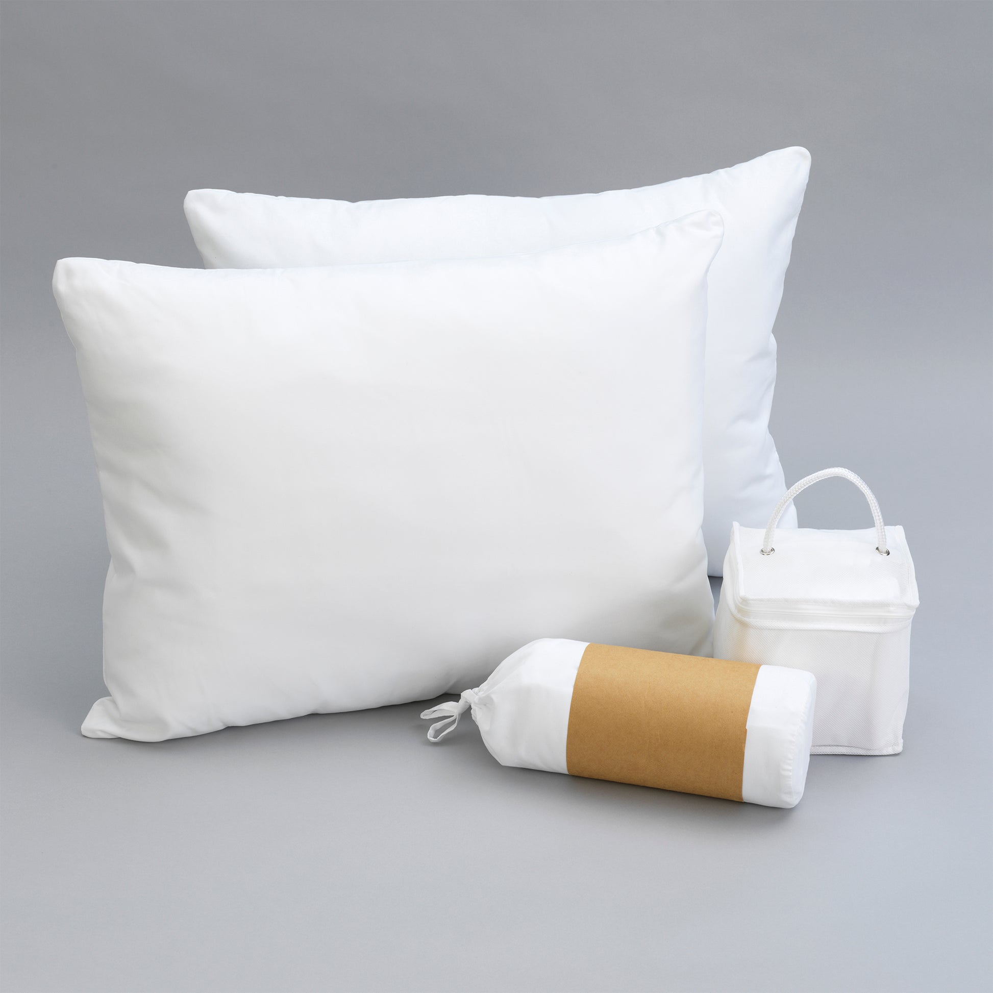 Two white down alternative pillows and rolled bedding with brown band on grey